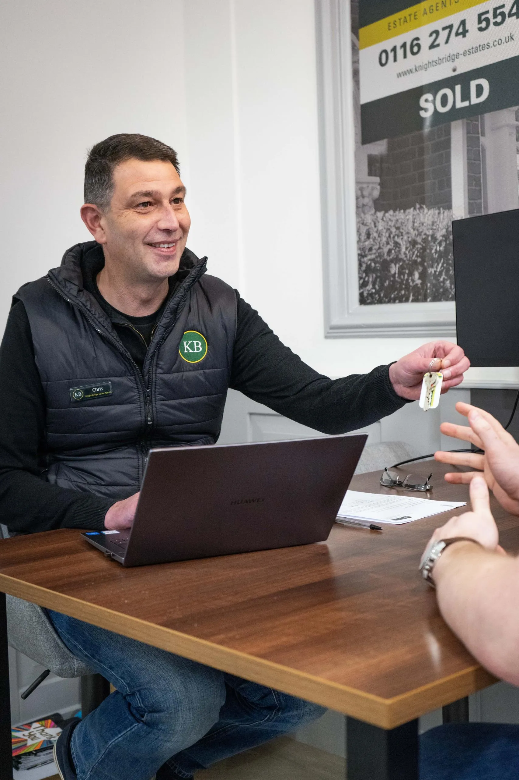 Estate agent handing over property keys across a desk, completing a tenancy agreement with a client