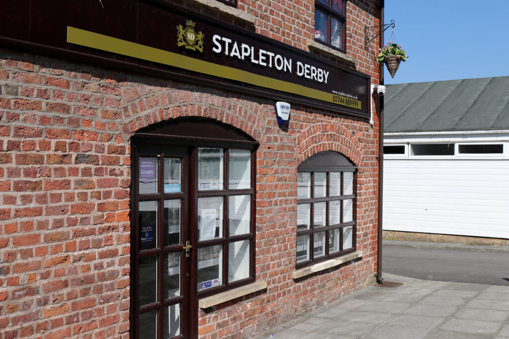 Stapleton Derby storefront with red brick facade and property window displays