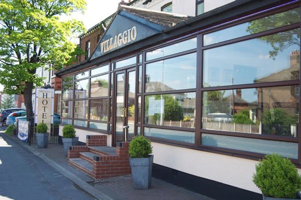 Viaggio restaurant storefront with large windows, brick base, and potted plants outside
