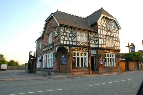 Historic half-timbered building with brick lower storey and gabled roof, featuring "The Stoop Inn" storefront at street level