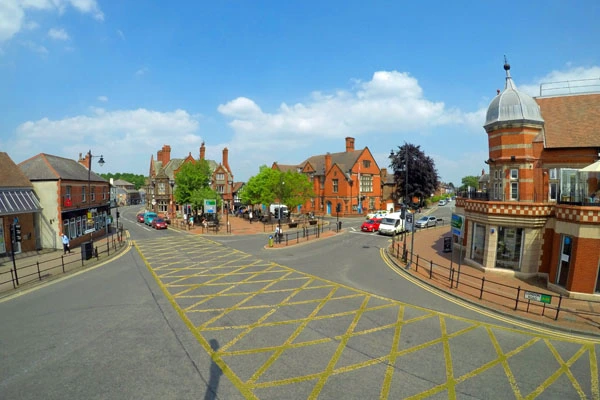 Town square with brick buildings, shops, and a distinctive domed tower, yellow road markings in foreground