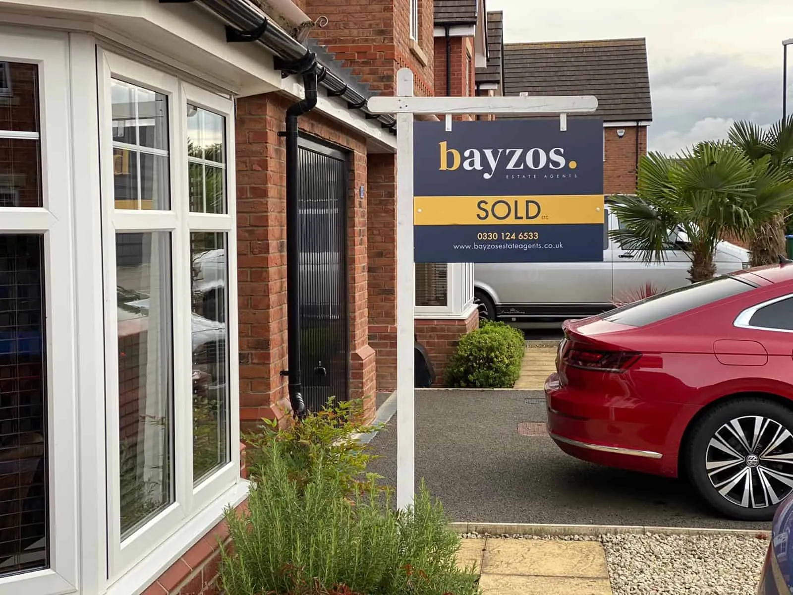A Bayzos estate agents sold board outside a house on a modern estate