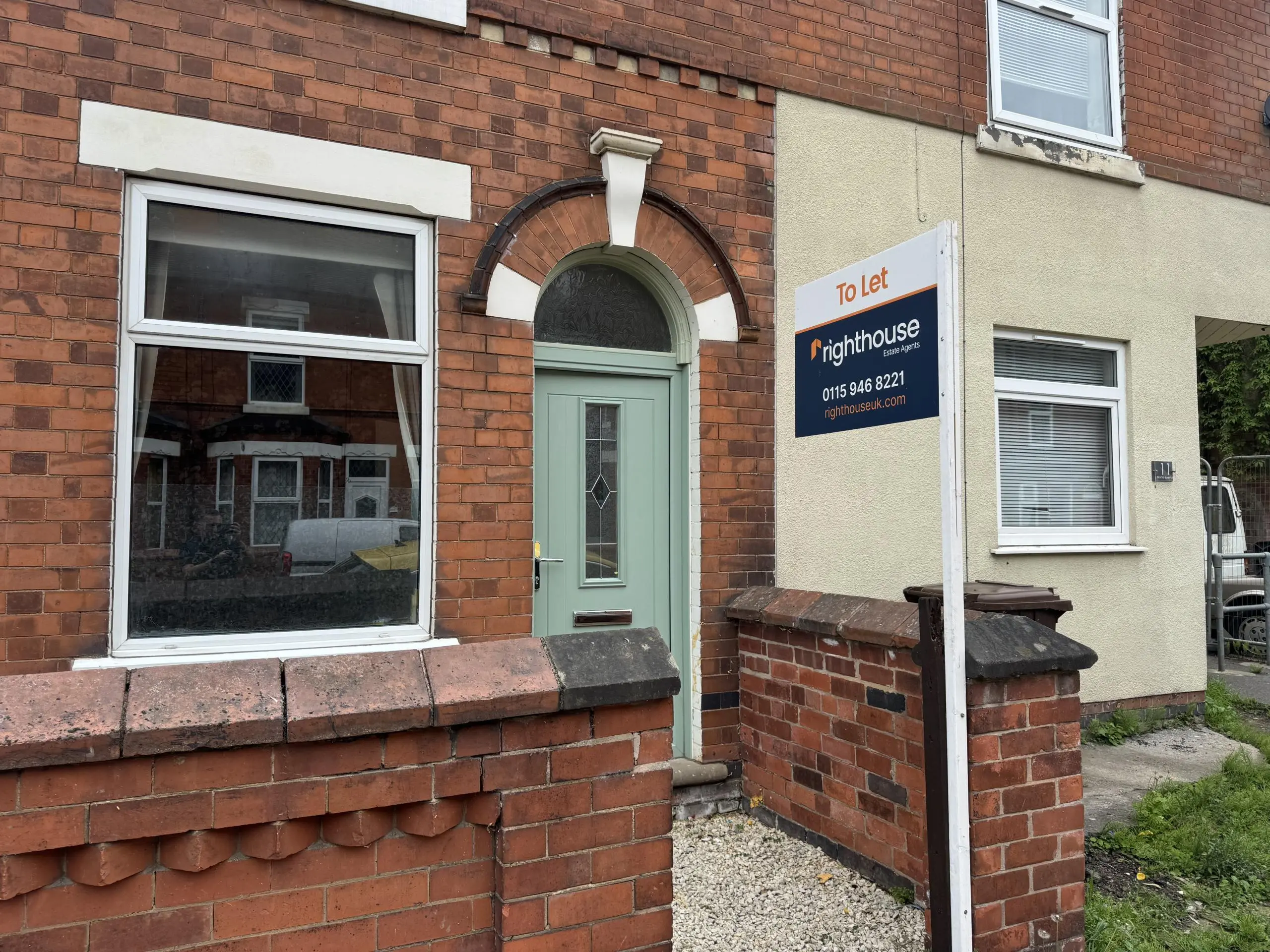 Red brick terraced house with green arched door, white-framed window, and "To let" estate agent sign for Righthouse