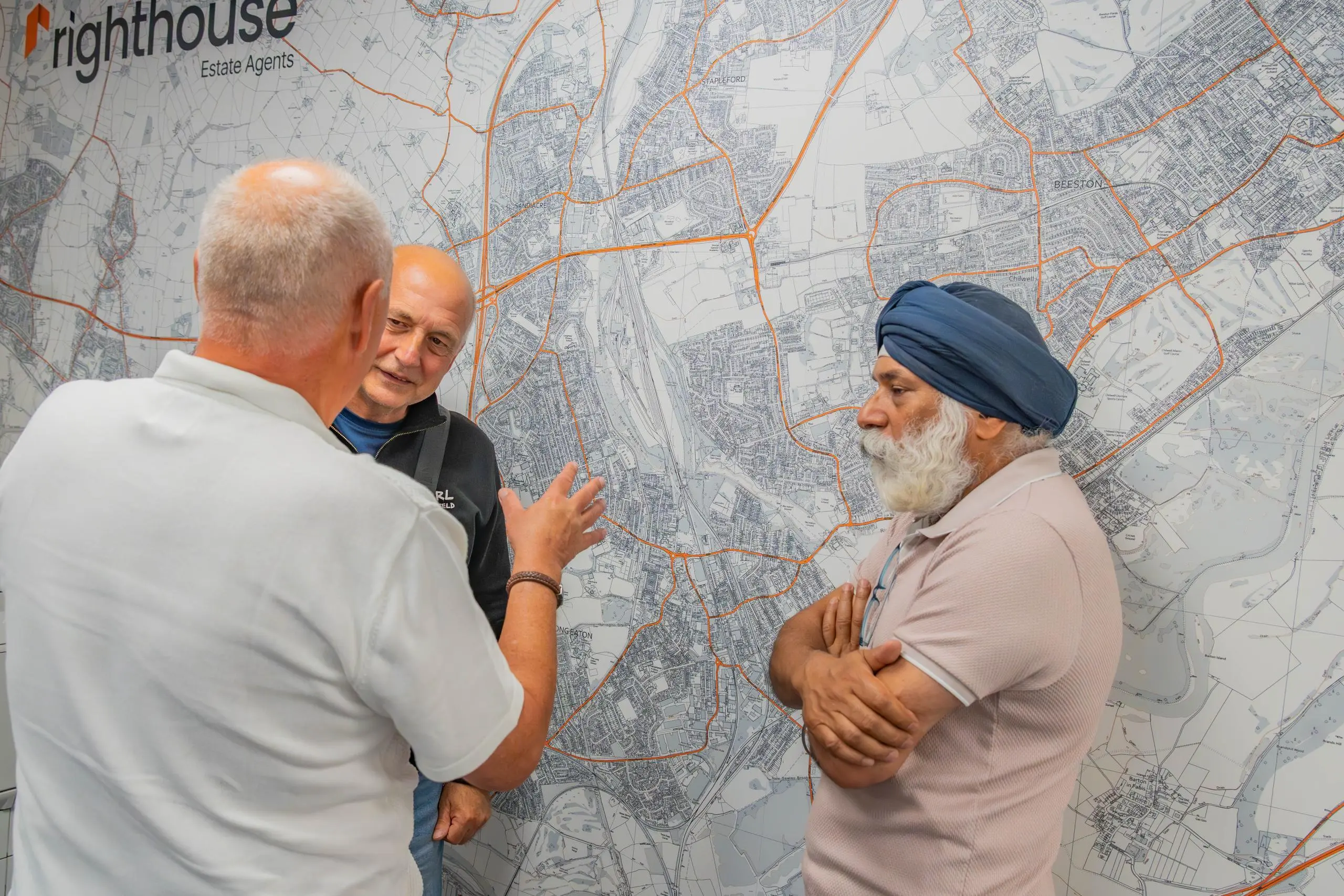 Three people standing in front of a large street map with orange route lines and Righthouse Estate Agents logo