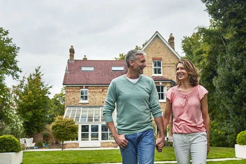 Couple walking in garden in front of stone house