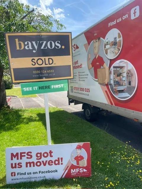 A Bayzos sold board in front of an MFS Solutions Removals van