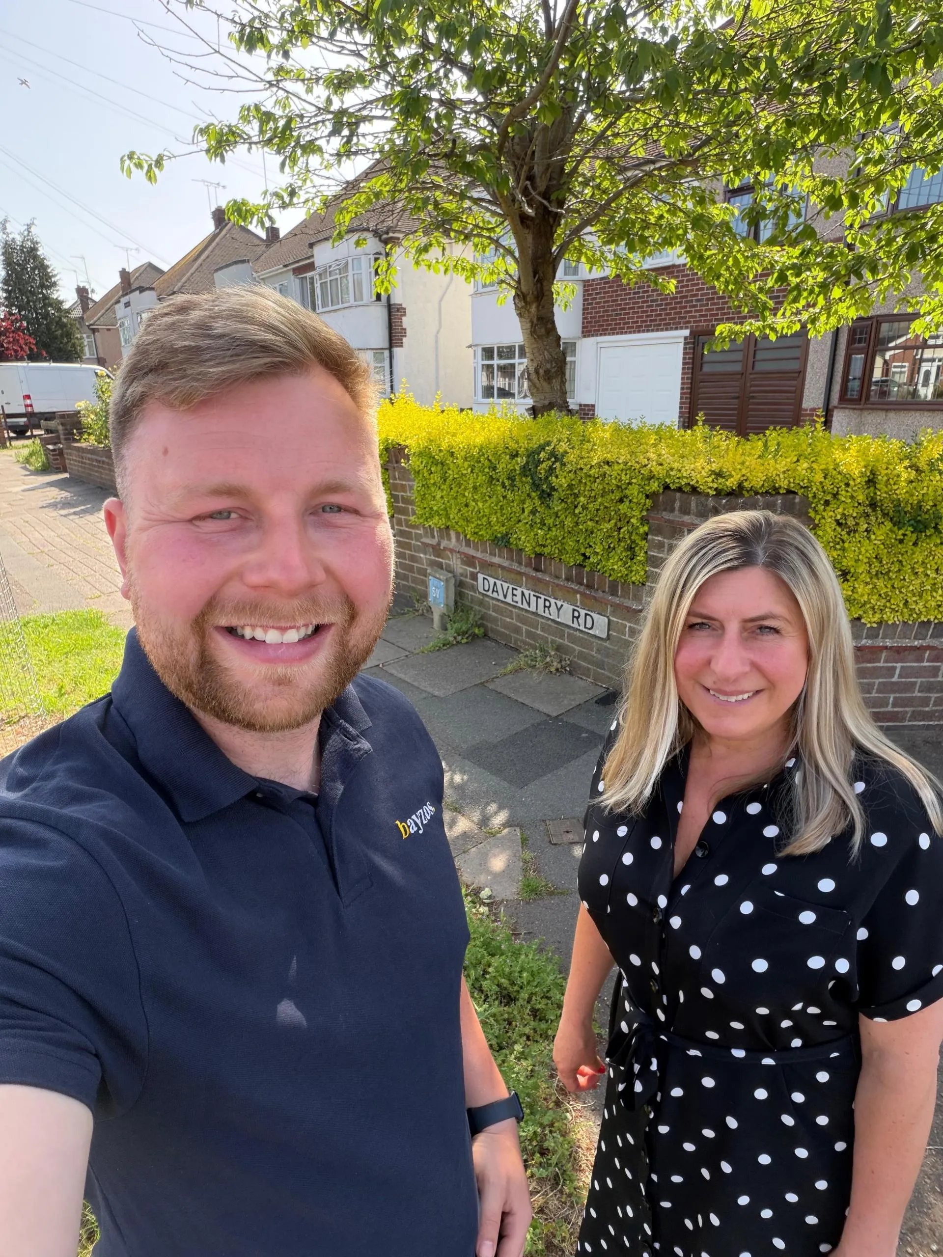 James and Becky from the Bayzos team are outside, smiling at the camera