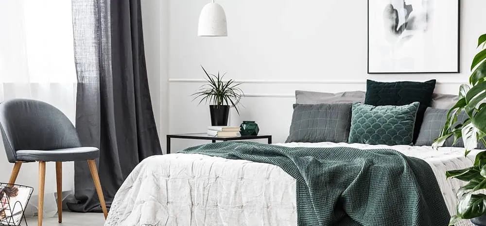 Contemporary bedroom with teal and grey bedding, pendant light, and potted plants