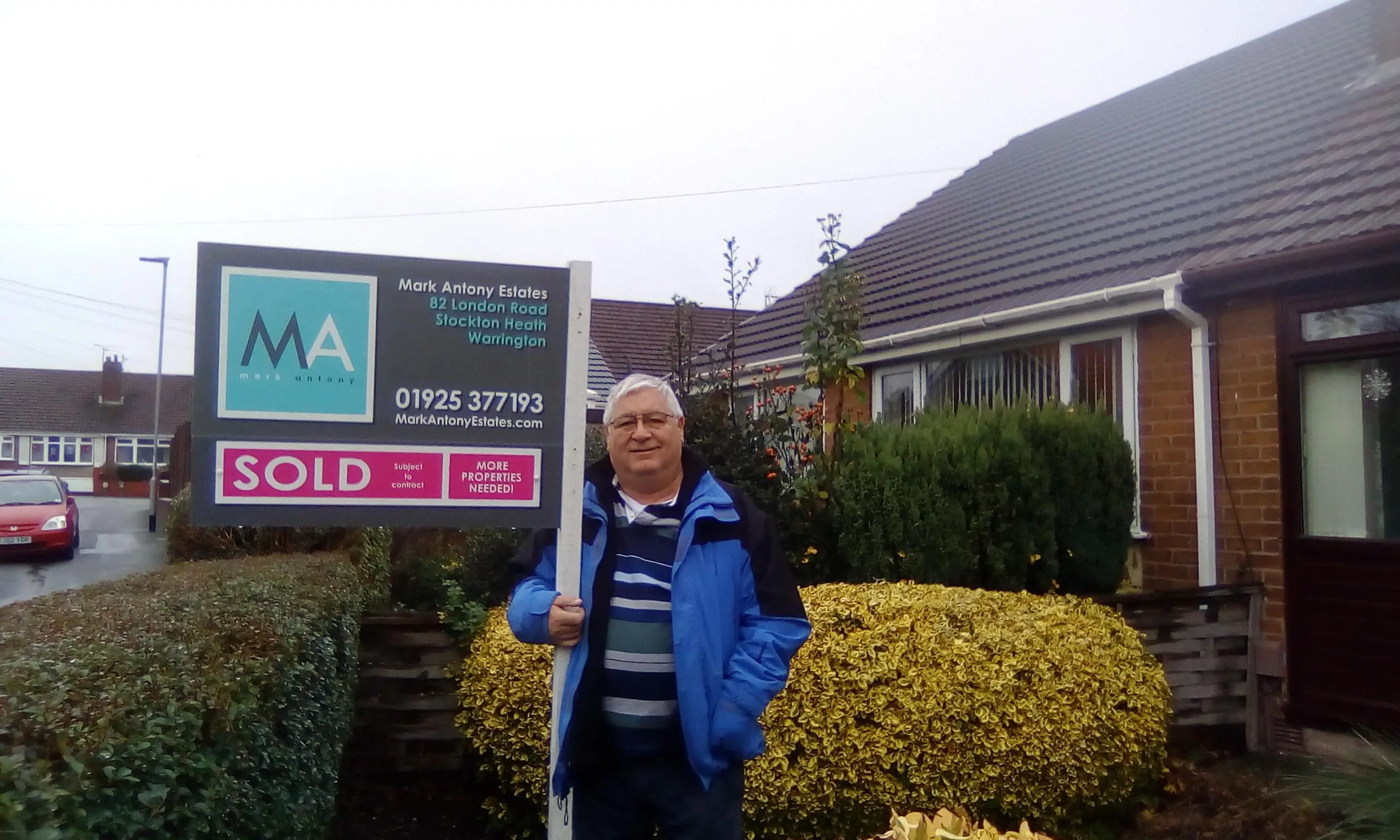 Man in blue jacket standing in front of property with Mark Antony Estates "SOLD" sign