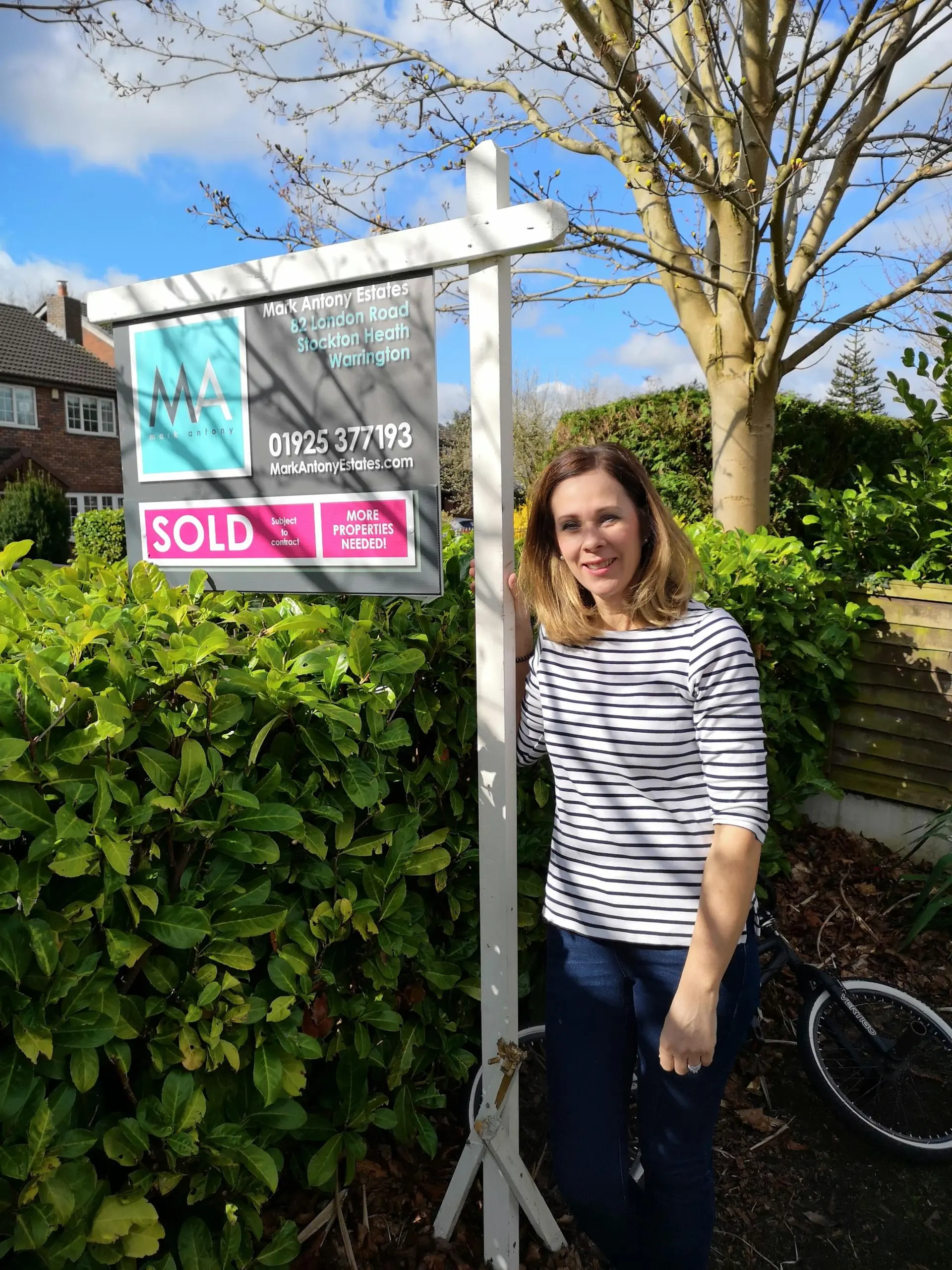 Woman standing next to Mark Antony Estates sold sign, 42 Mill Lane, Stockton Heath, Warrington