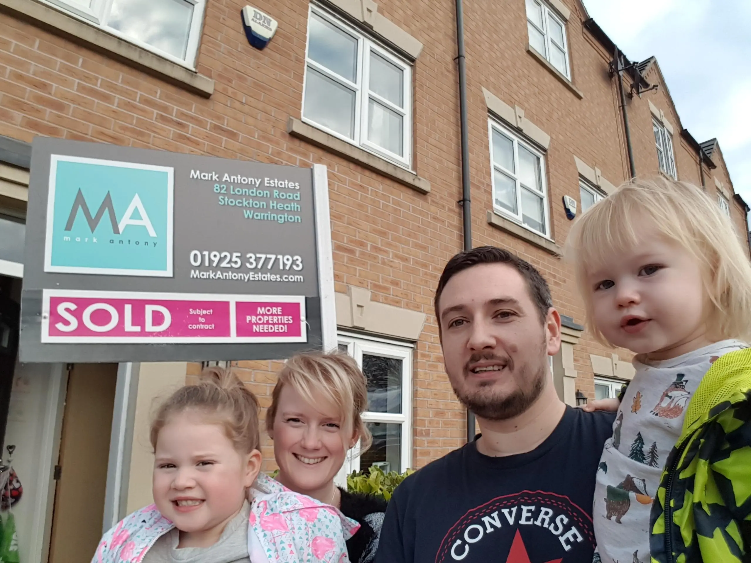 Four people standing in front of a brick building with a Mark Antony Estates "SOLD" sign reading "82 London Road, Stockton Heath, Warrington"