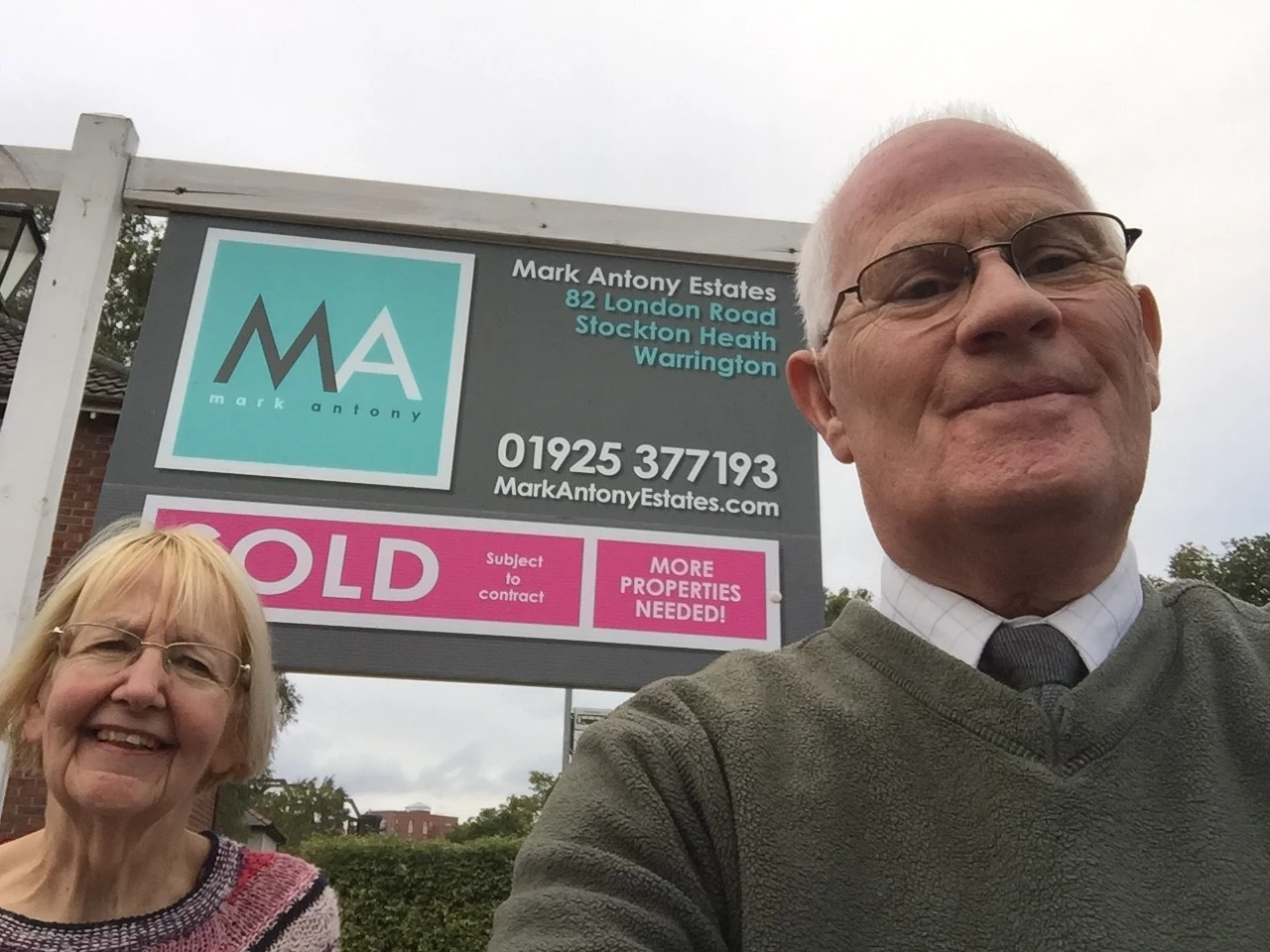 Two people standing in front of a Mark Antony Estates sold board displaying "82 London Road, Stockton Heath, Warrington"