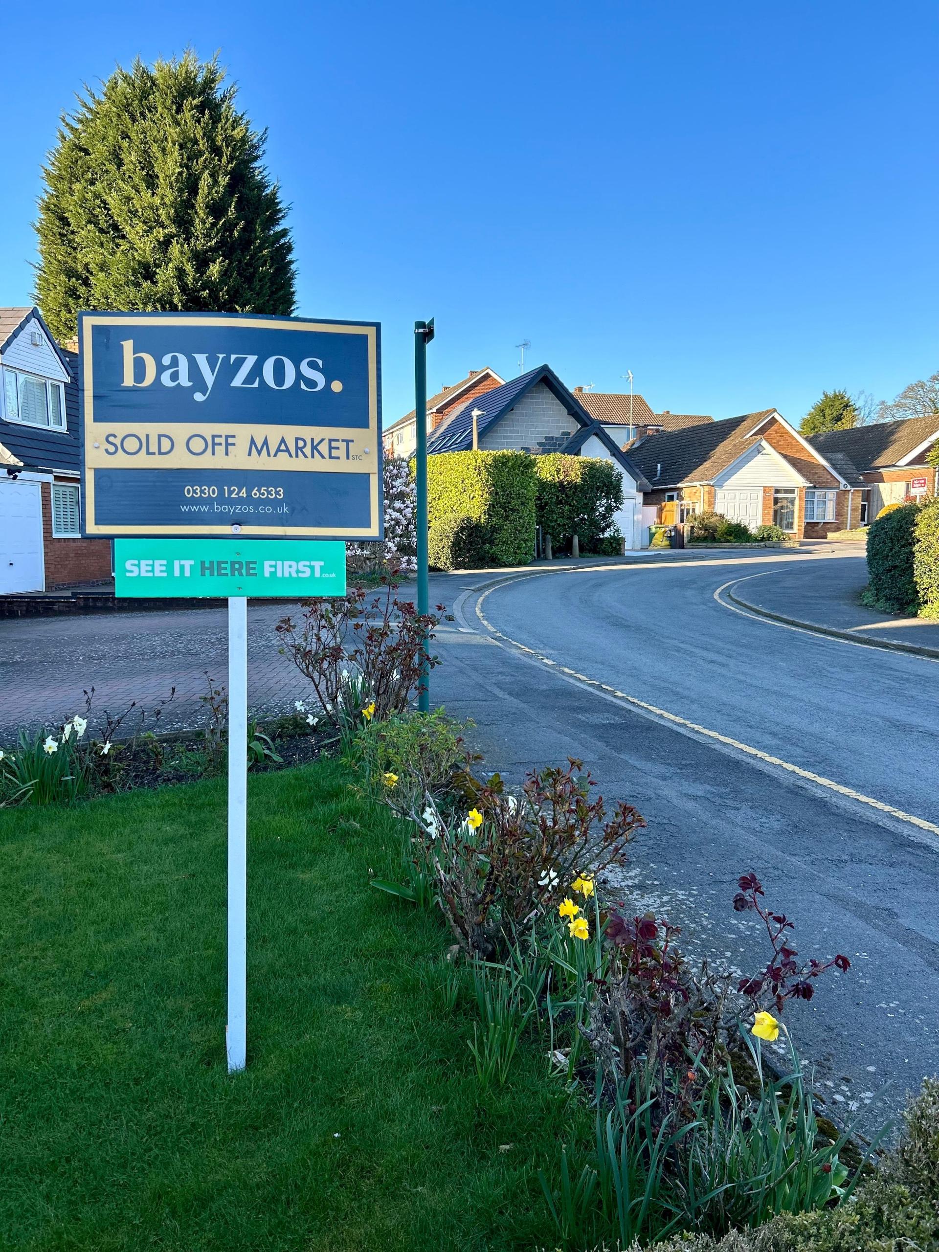 A sold off market board stands in front of a row of bungalows