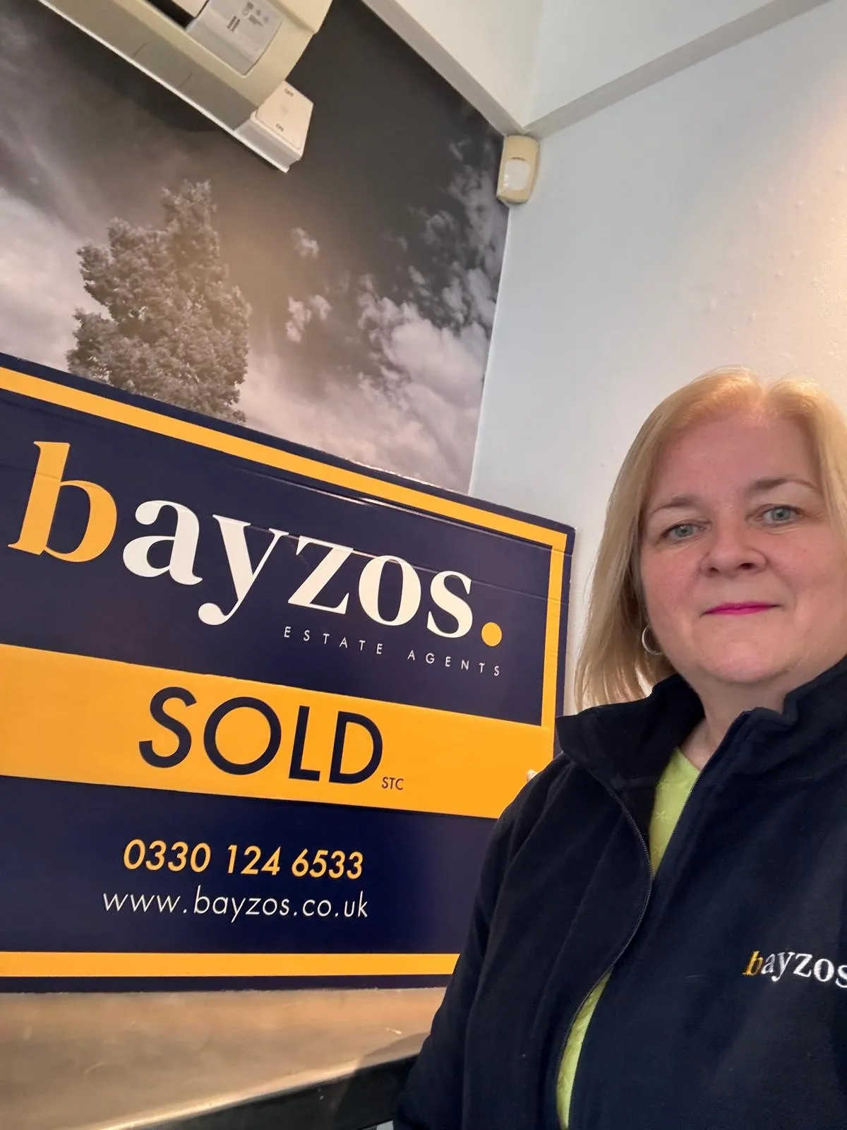 Karen, a sales progressor at Bayzos estate agents stands in front of a sold board