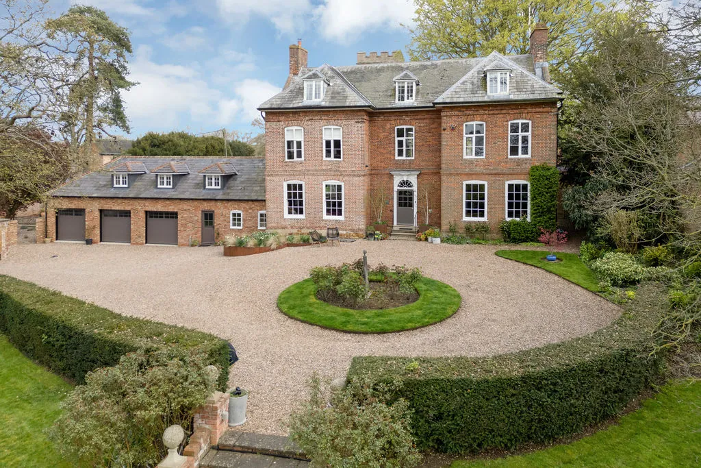 Large brick country house with circular gravel driveway and mature landscaped gardens