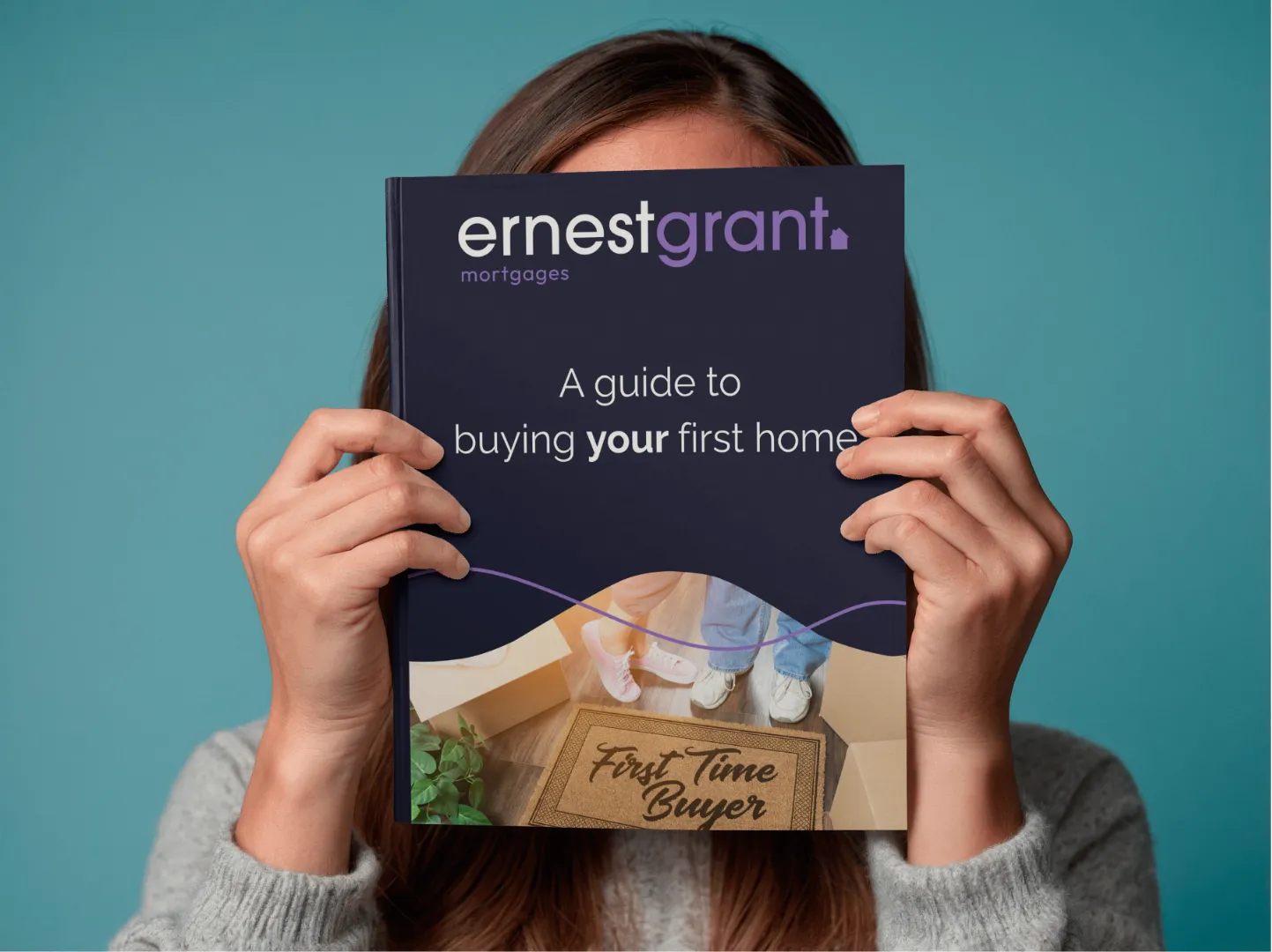 Person holding Ernest Grant Mortgages "A guide to buying your first home" booklet against turquoise background