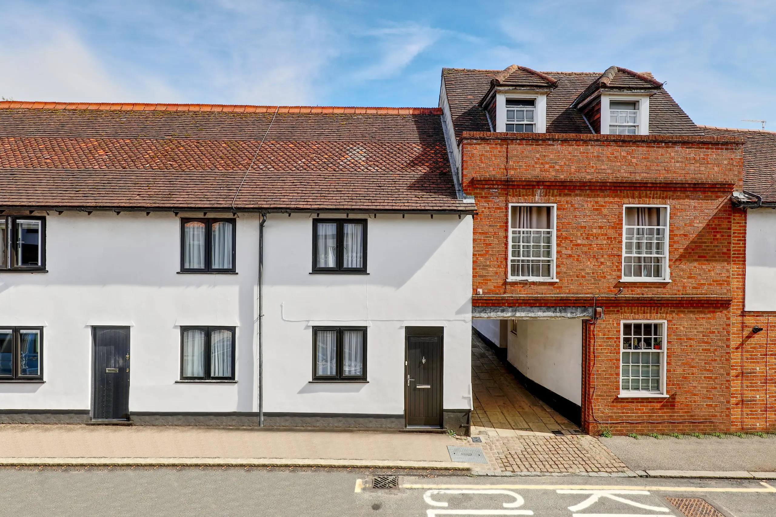 Terraced houses with white-rendered and red-brick facades, featuring dormer windows and dark wooden doors