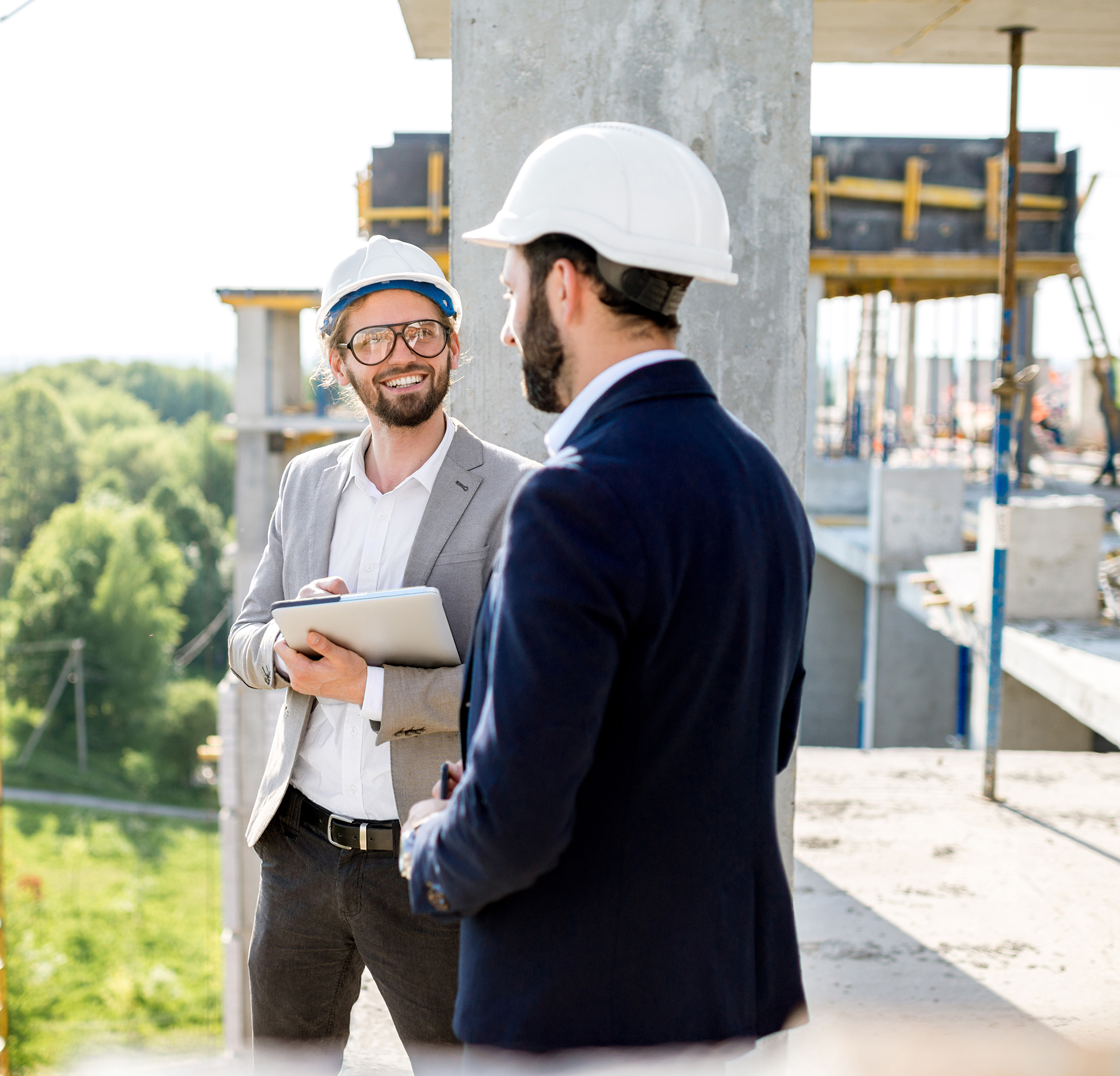 Two people wearing hard hats are talking on a construction site