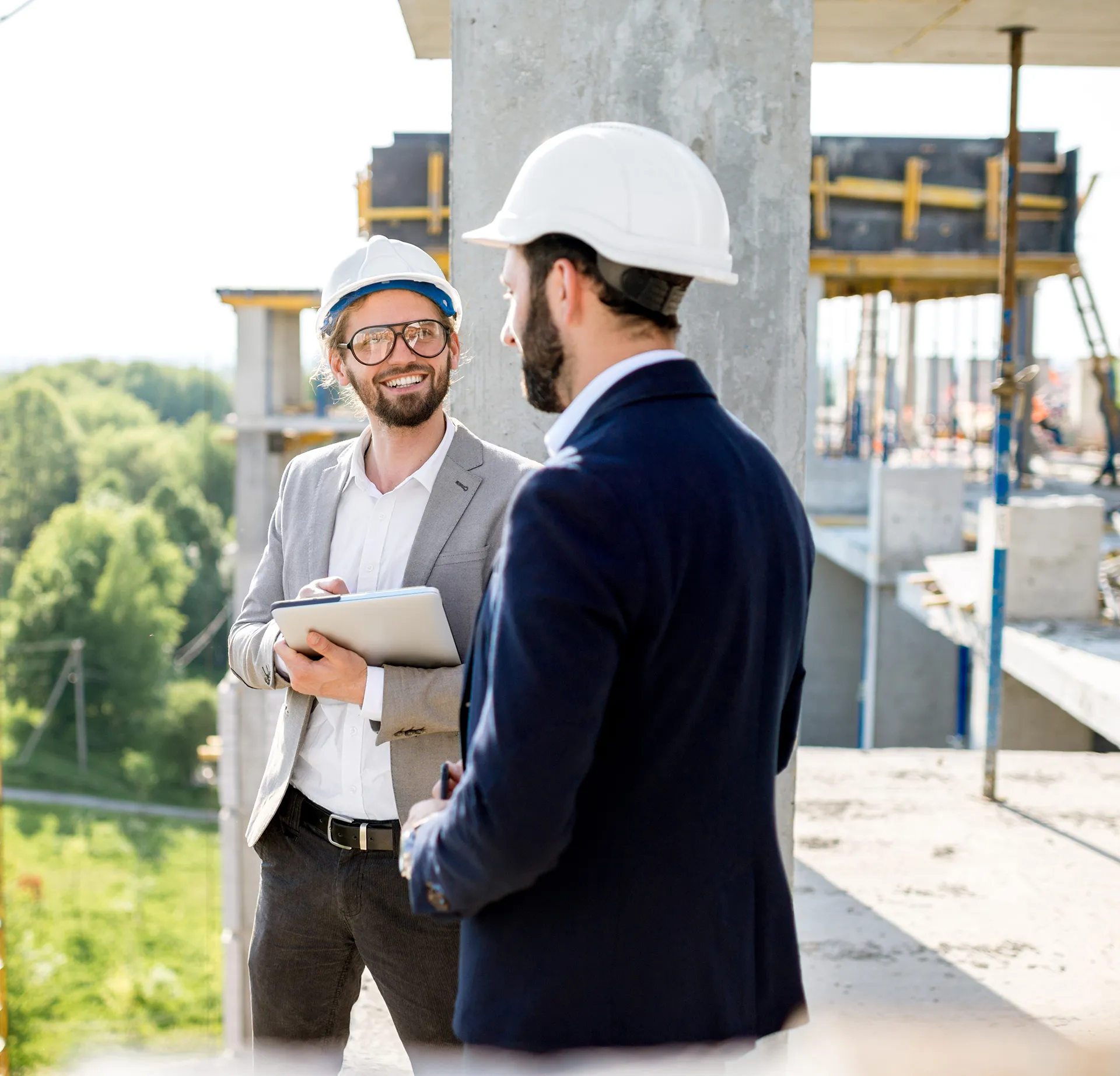 Two people wearing hard hats are talking on a construction site