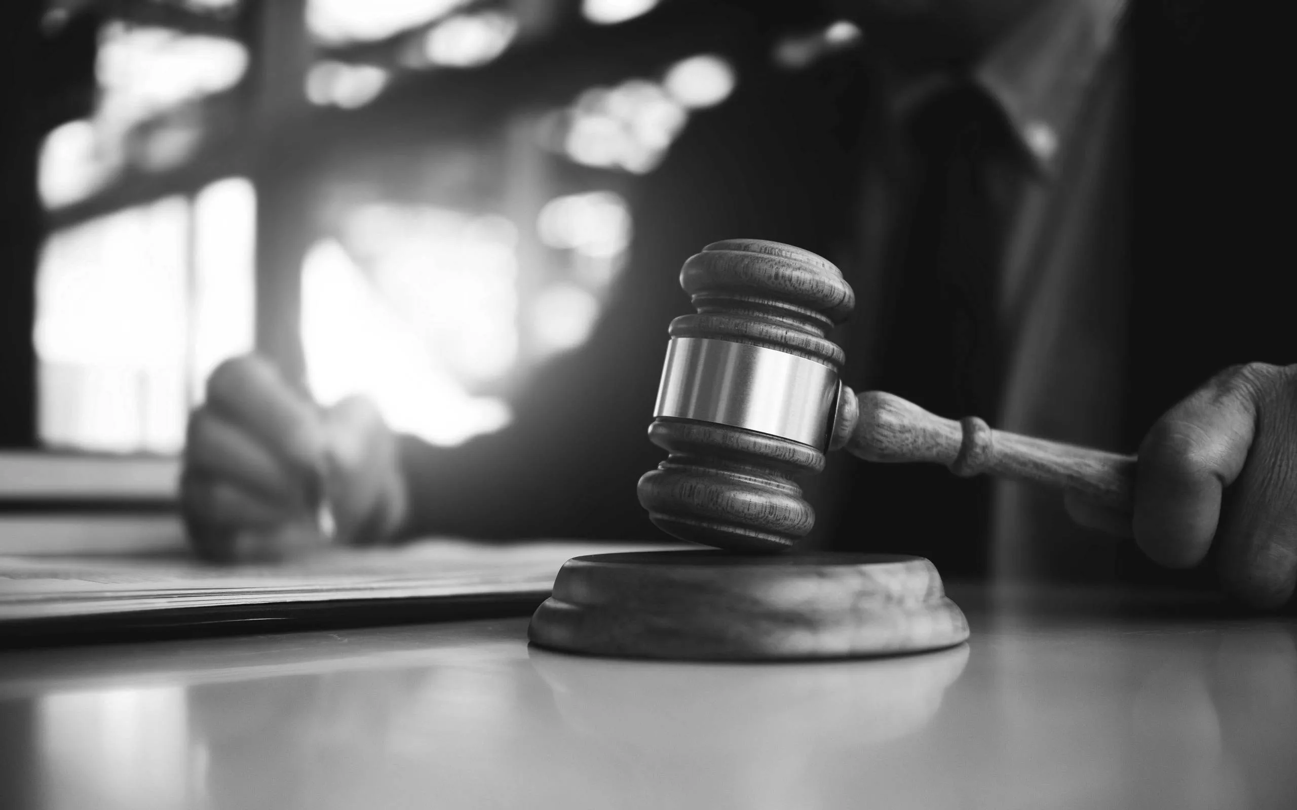 Judge's gavel on a wooden block with an open law book, black and white photograph