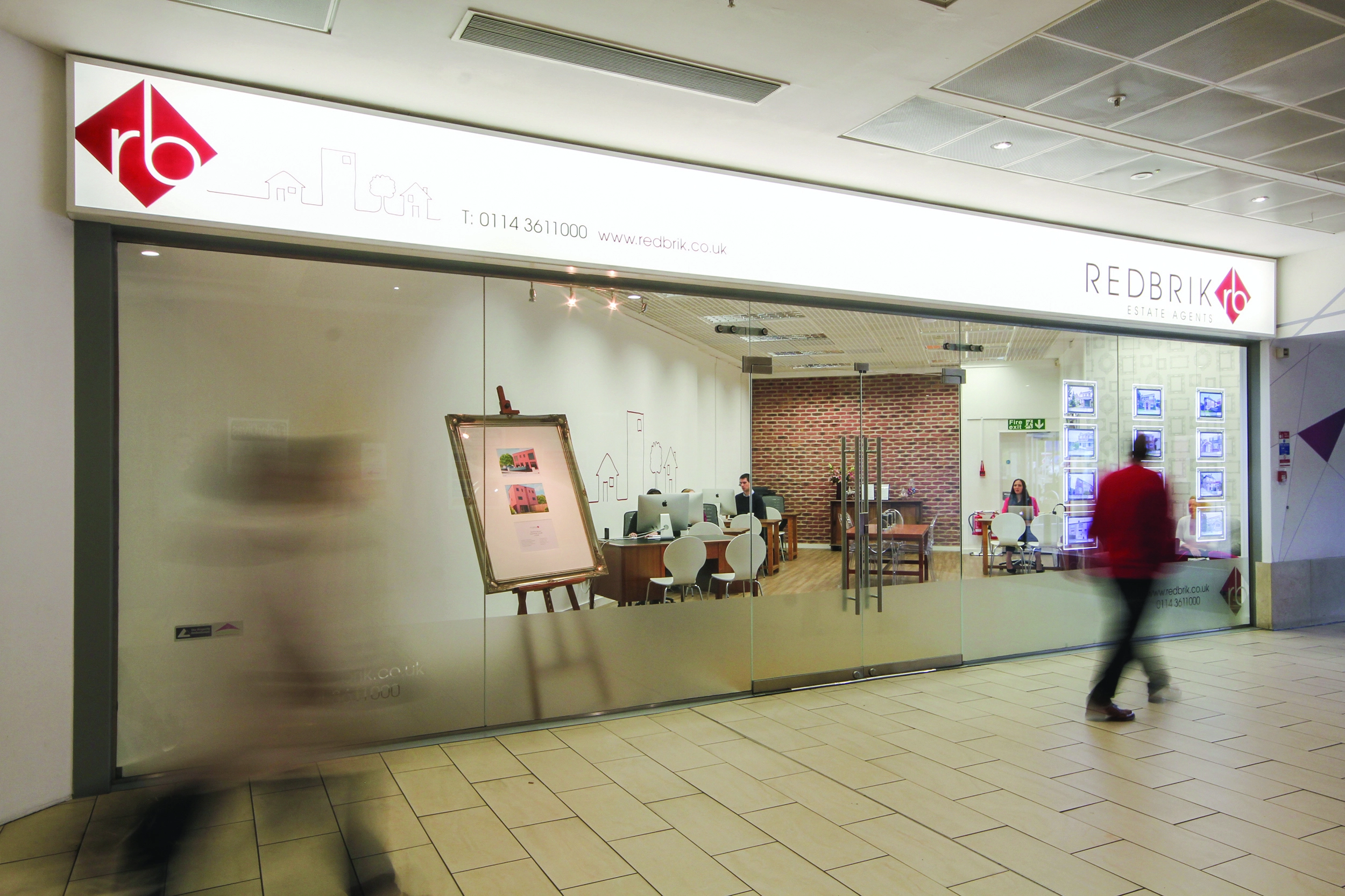 Redbrik Estate Agents shopfront with glass frontage, red logo, and contact details T 0114 3611000 www.redbrik.co.uk