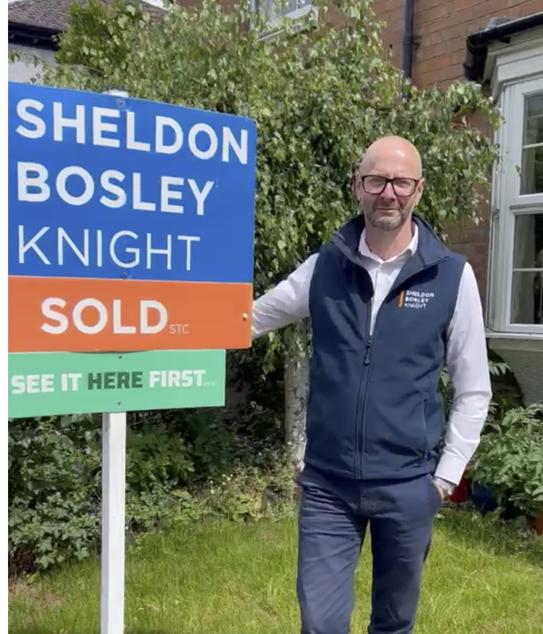 Ian from Sheldon Bosley Knight stands next to a Sold Board showing the See It Here First logo