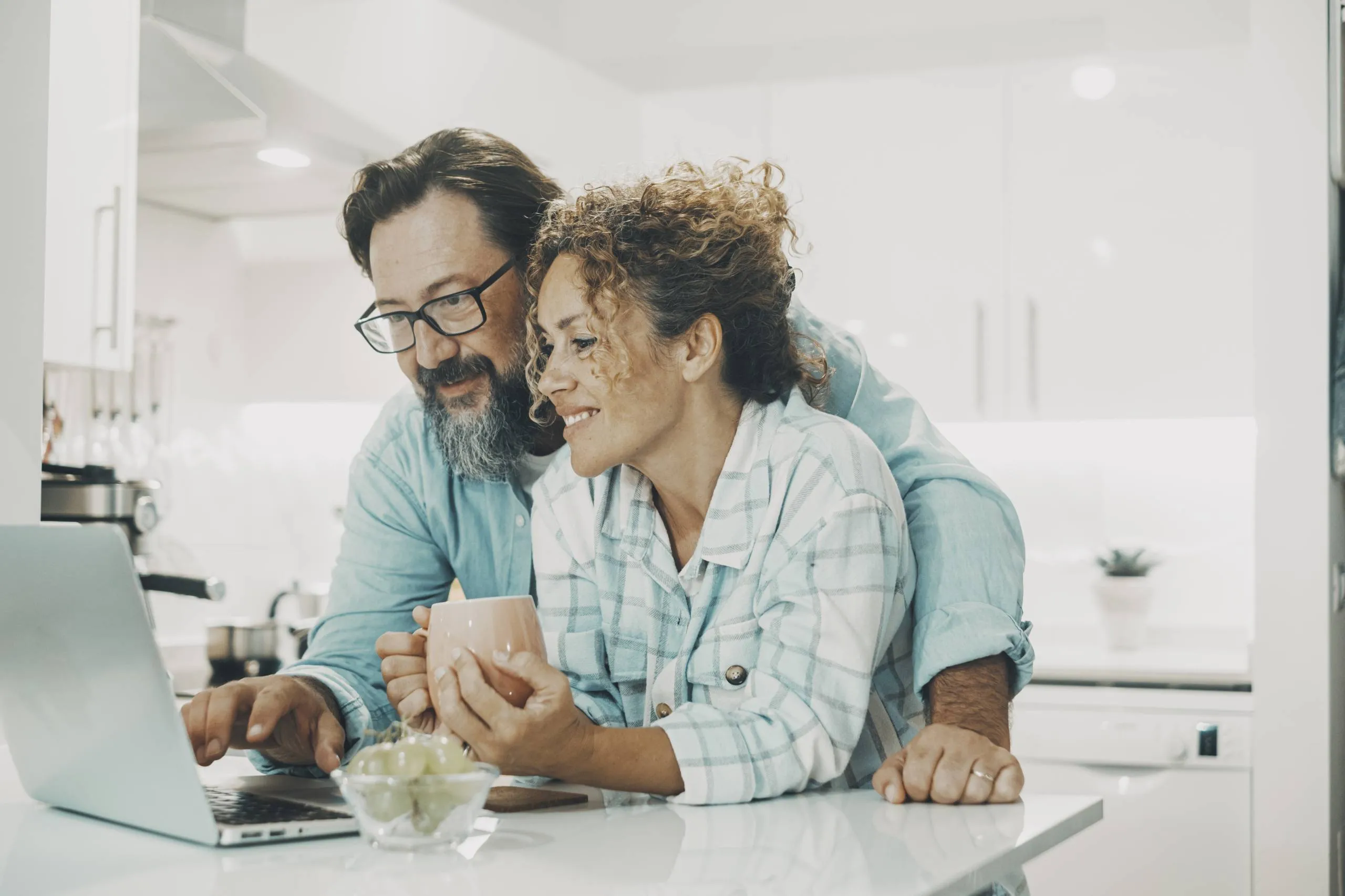 Two people smiling, leaning over a laptop