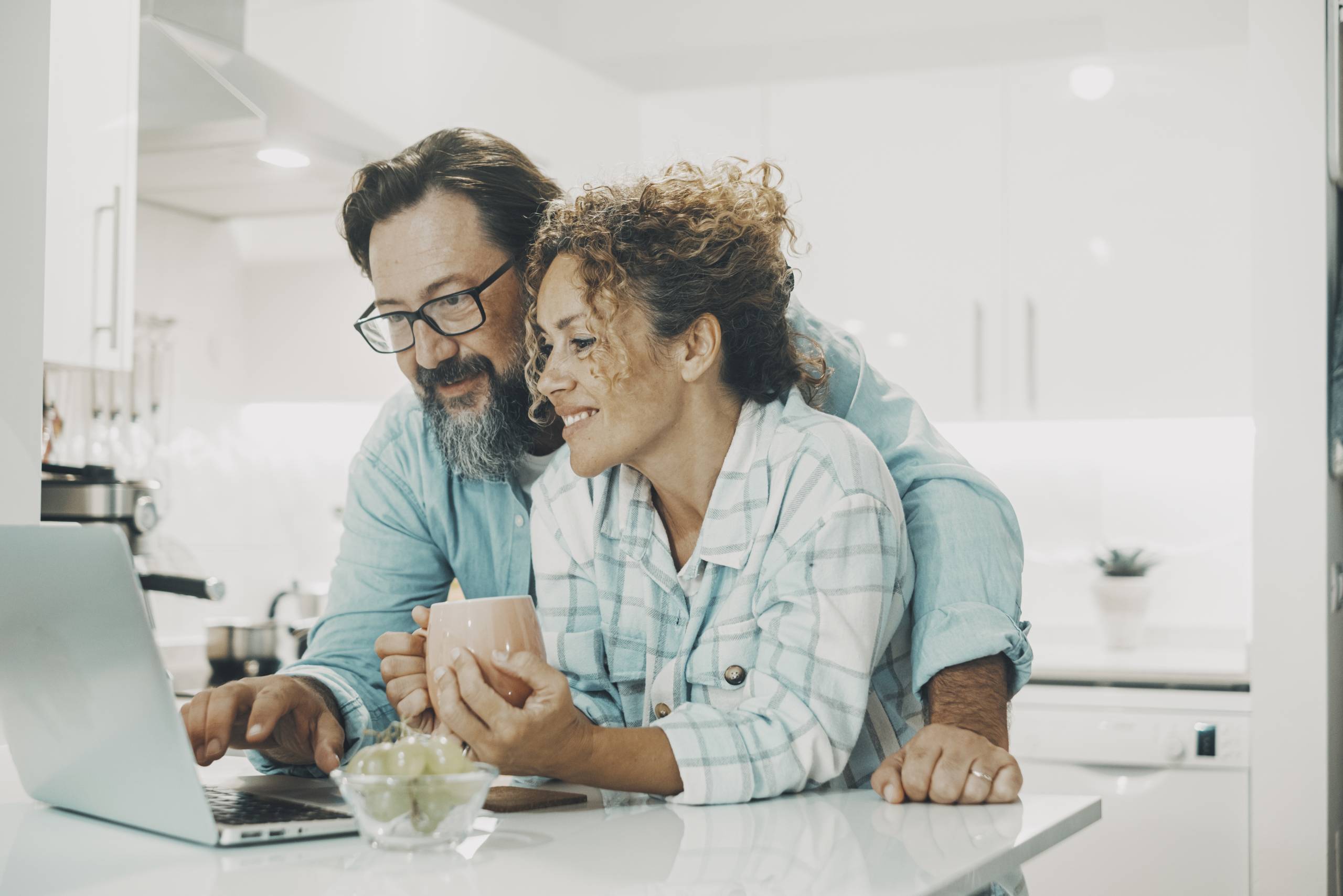 Two people smiling, leaning over a laptop