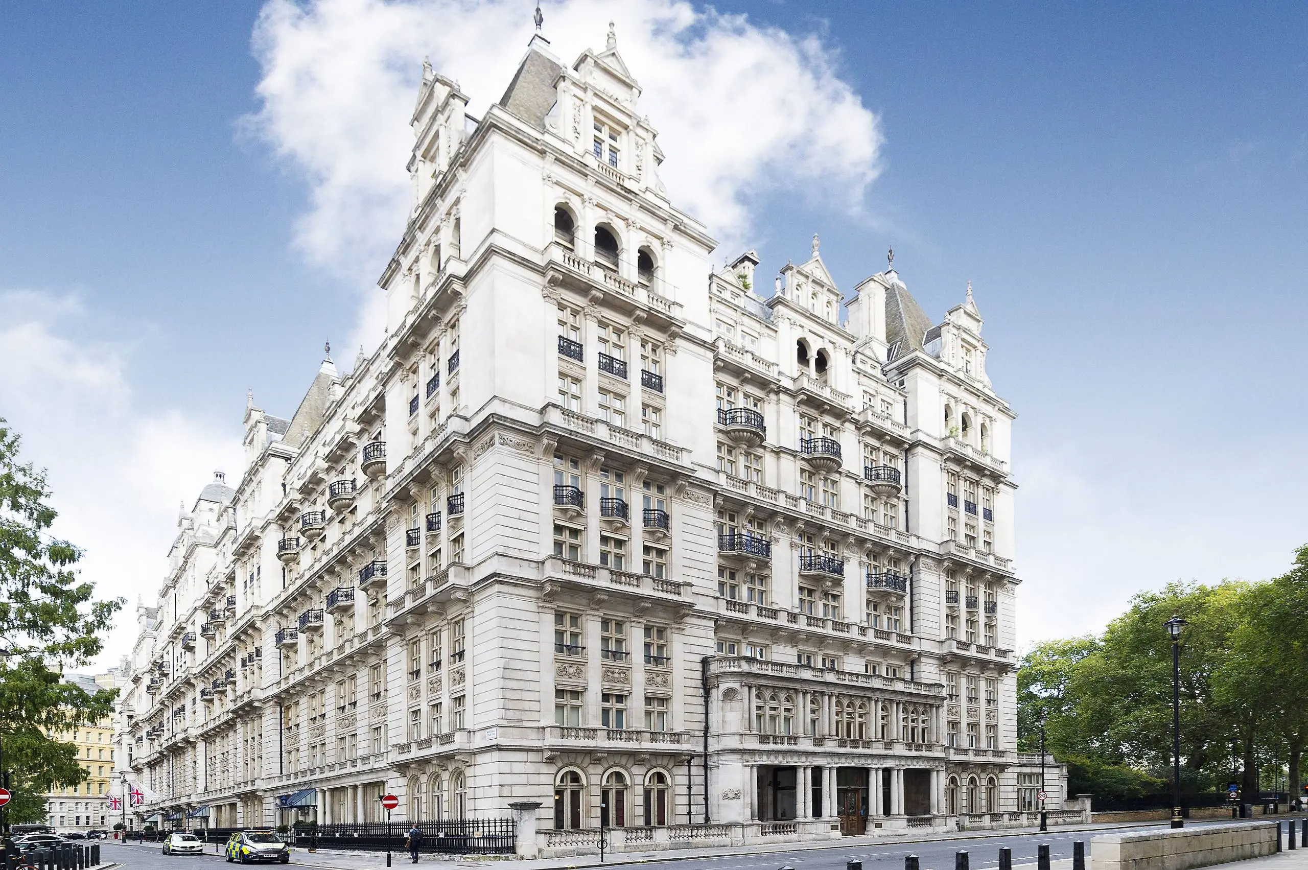 Ornate white stone building with mansard roofs and multiple storeys, featuring arched windows and decorative balconies on a London street