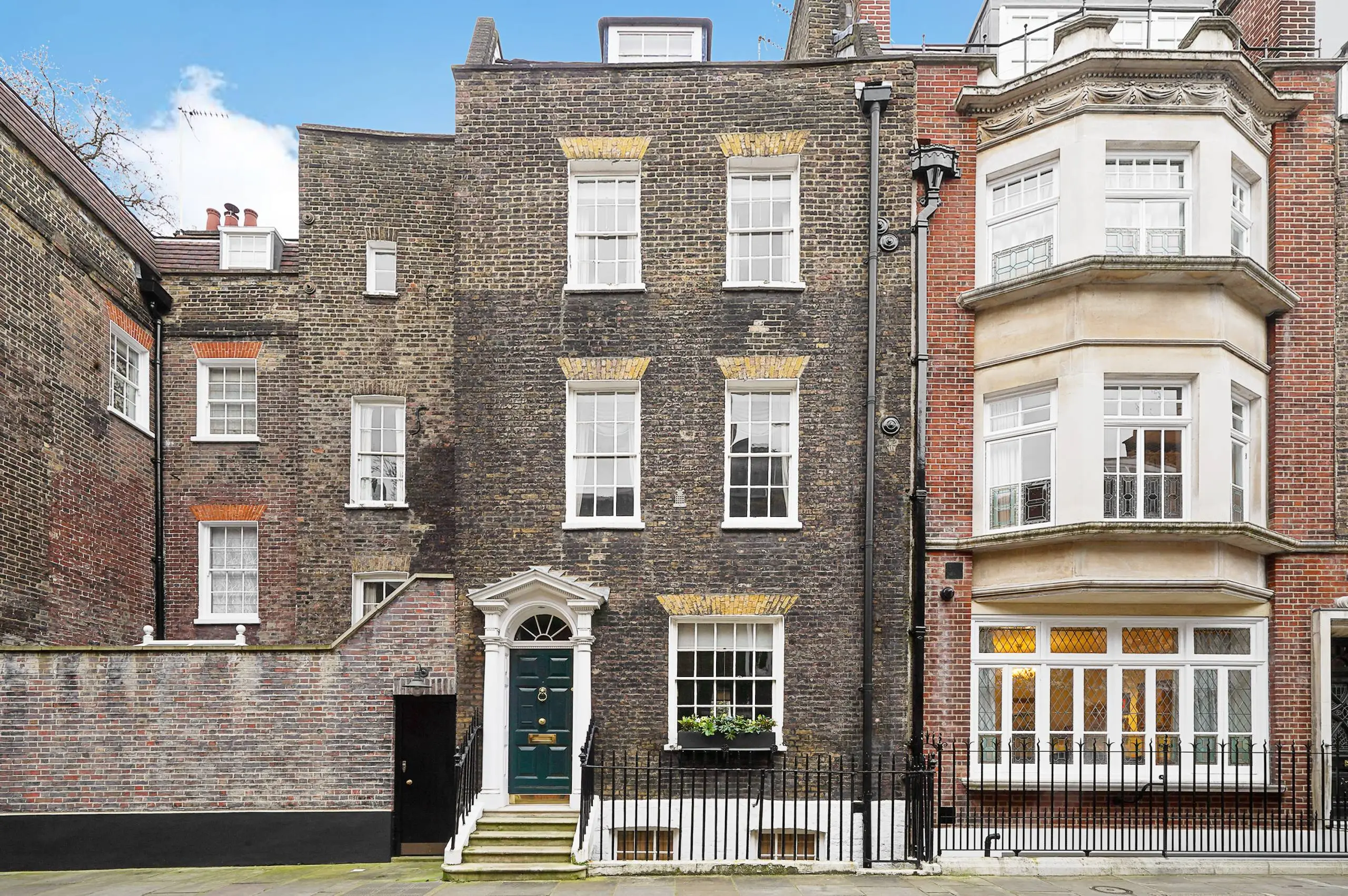 Terraced Georgian townhouses with dark brick facades, white-framed sash windows, and green front doors with white porches
