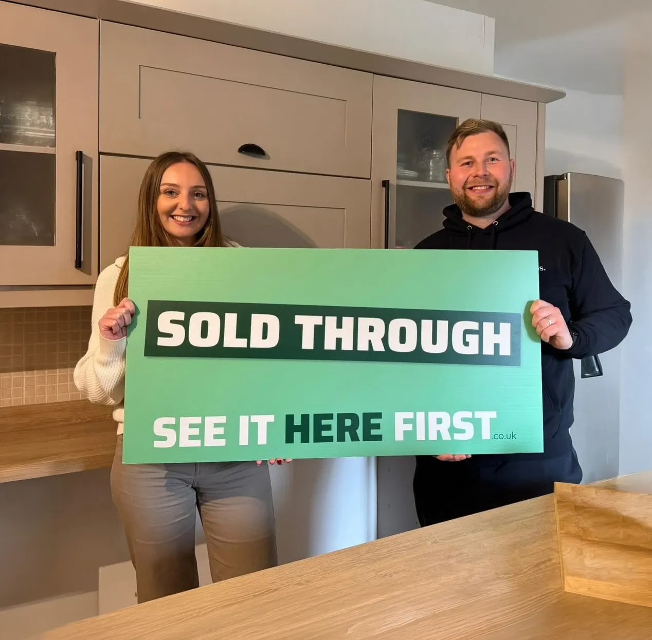 A seller who sold their property through see it here first, holding a board saying "sold through see it here first"