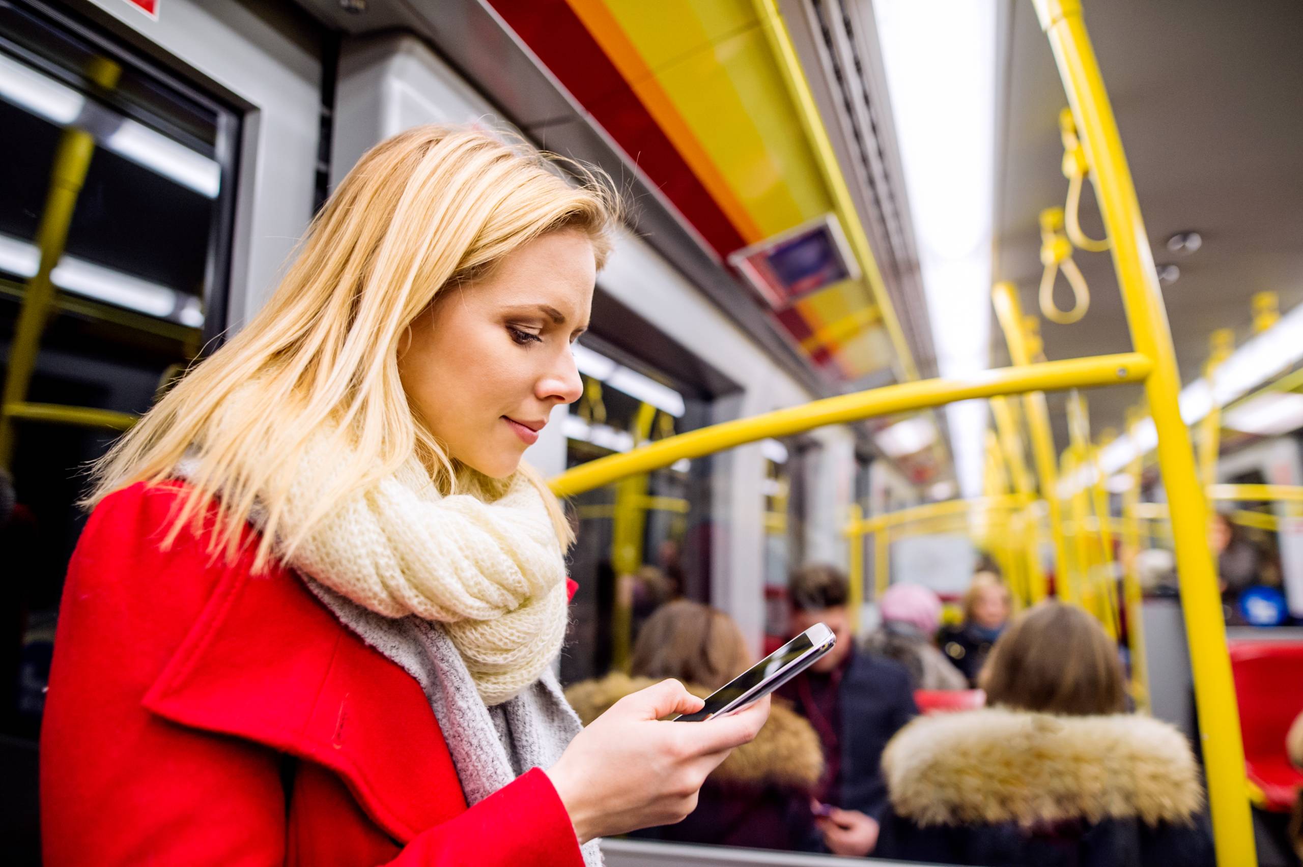 A commuter on  atrain vieiwng information on their smartphone