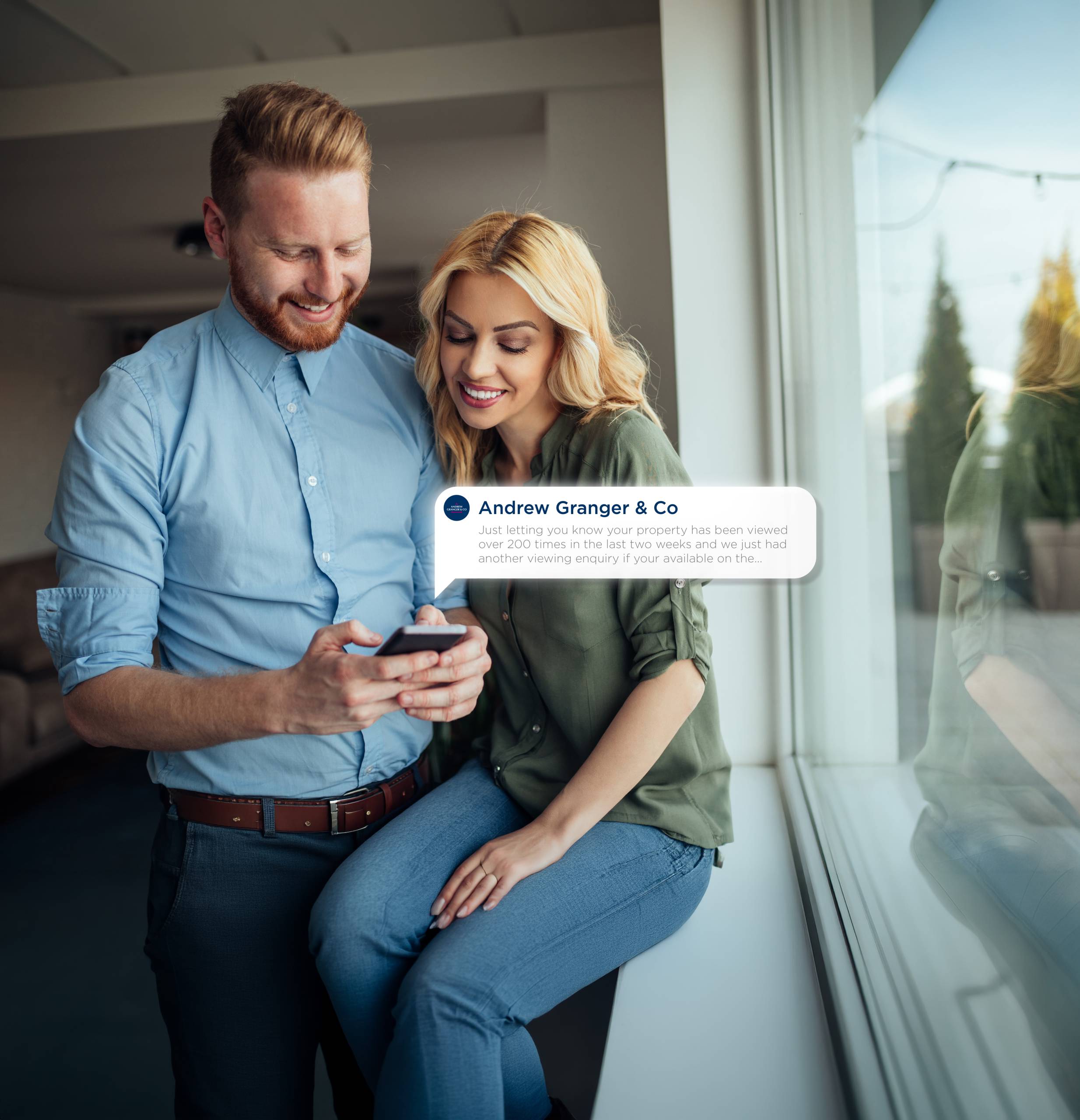A couple look at their phone, which displays a notification from the Andrew Granger Buyer App