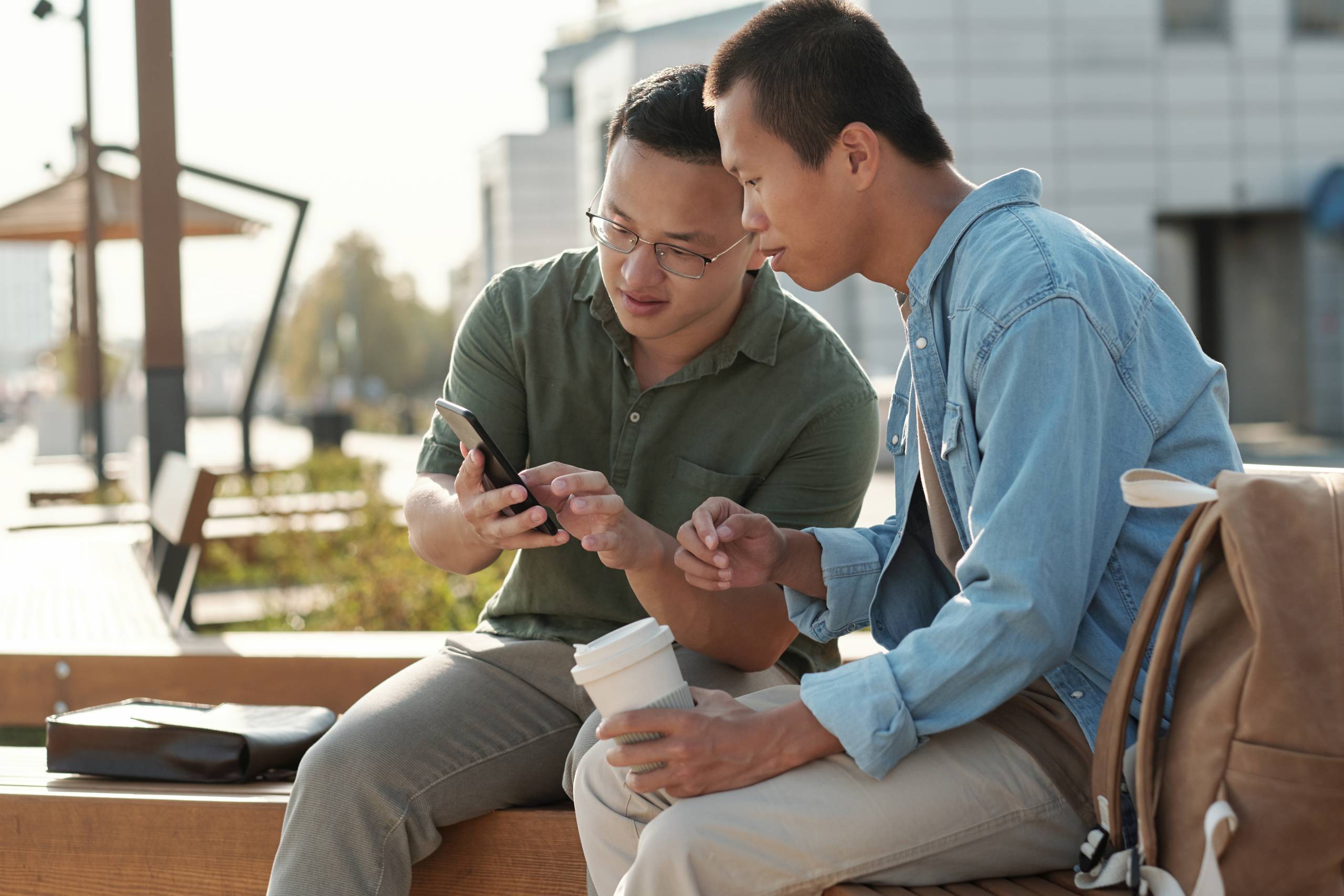 2 people sit and look at something on a phone screen
