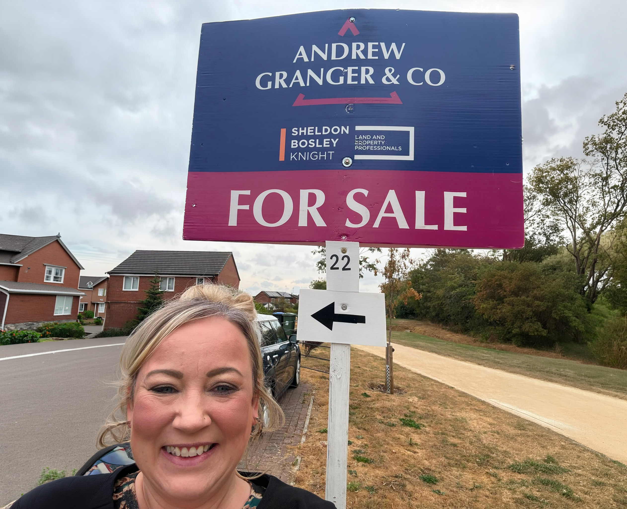 Sally from Andrew Granger stands in front of a for sale board in market harborough
