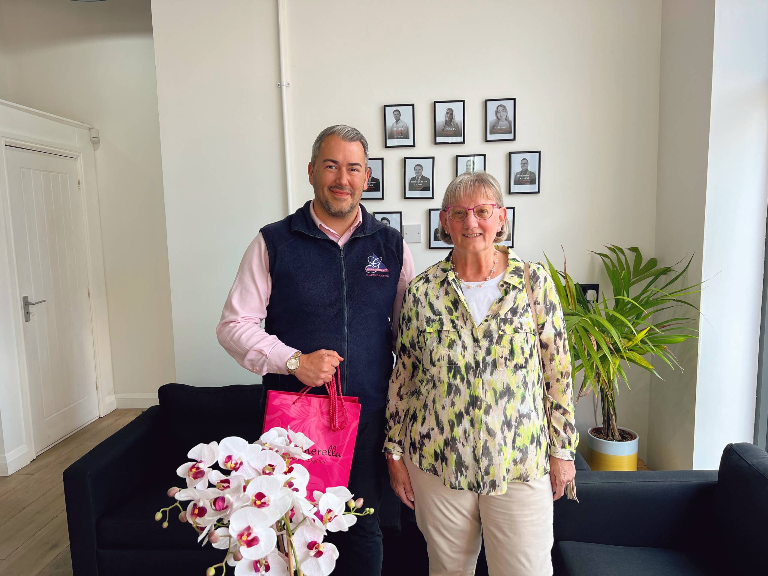 A sales manager from Andrew Granger's Oadby office stands with a homeowner, holding a gift and flowers