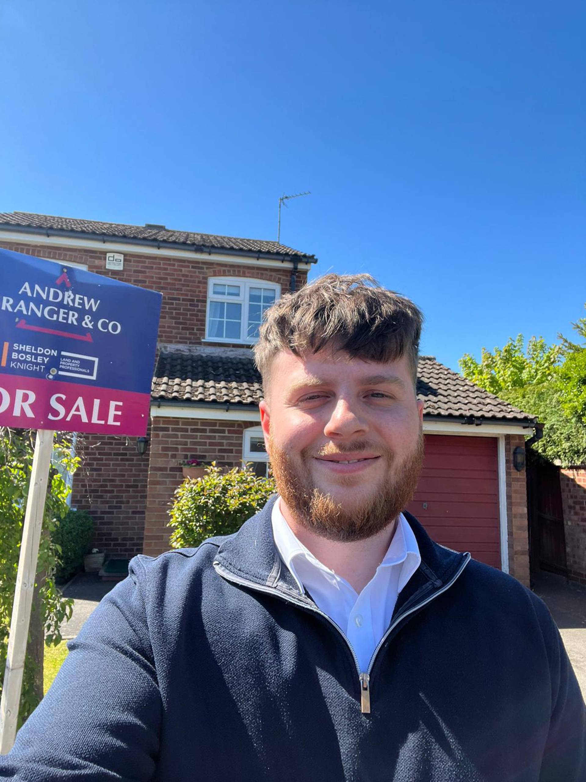 One of the Andrew Granger team stands next to a for sale board