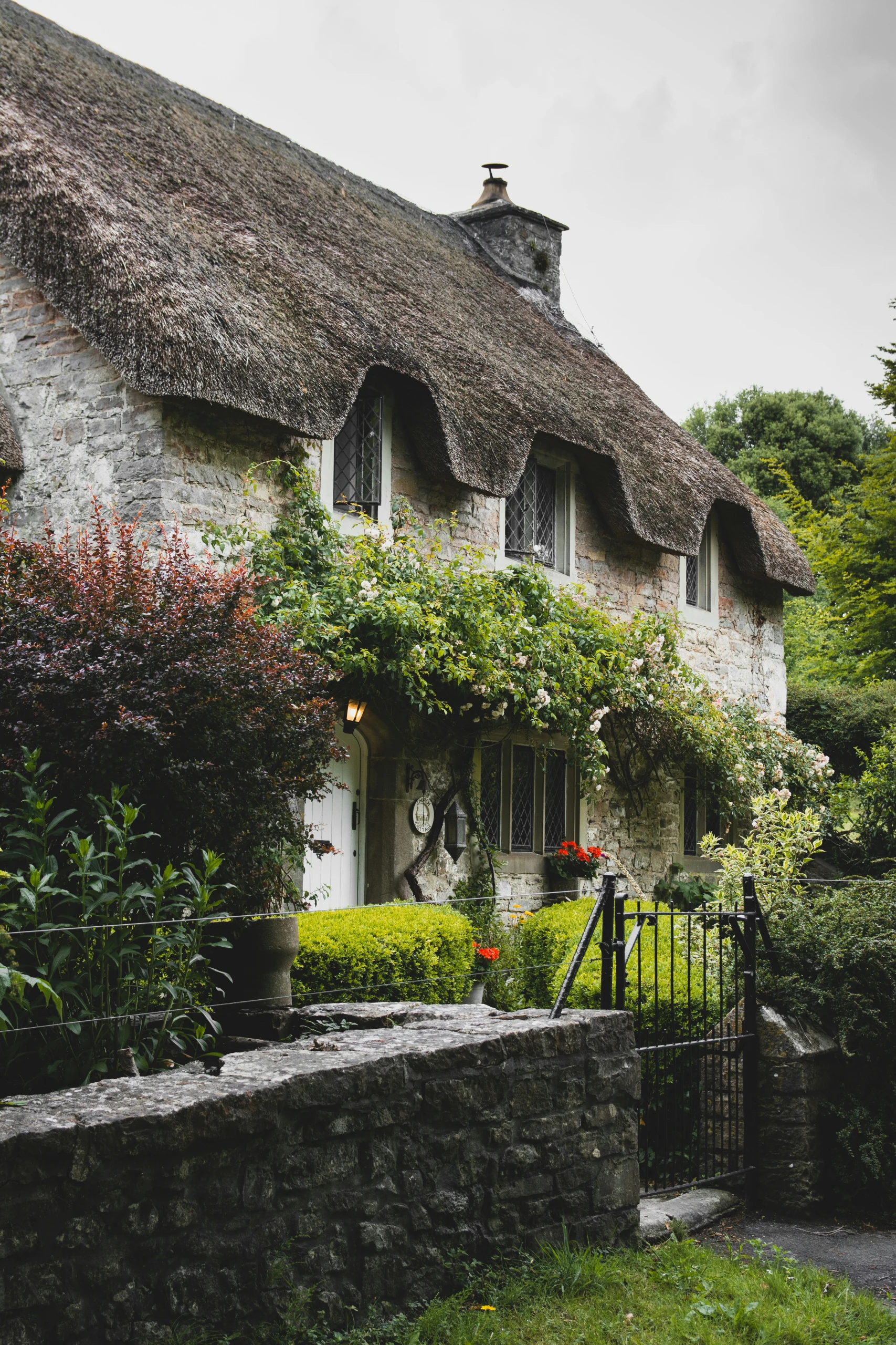 A charming stone cottage surrounded by lush greenery, representing the character properties Watkins Estate Agents helps clients buy and sell in Caerphilly and the surrounding areas.