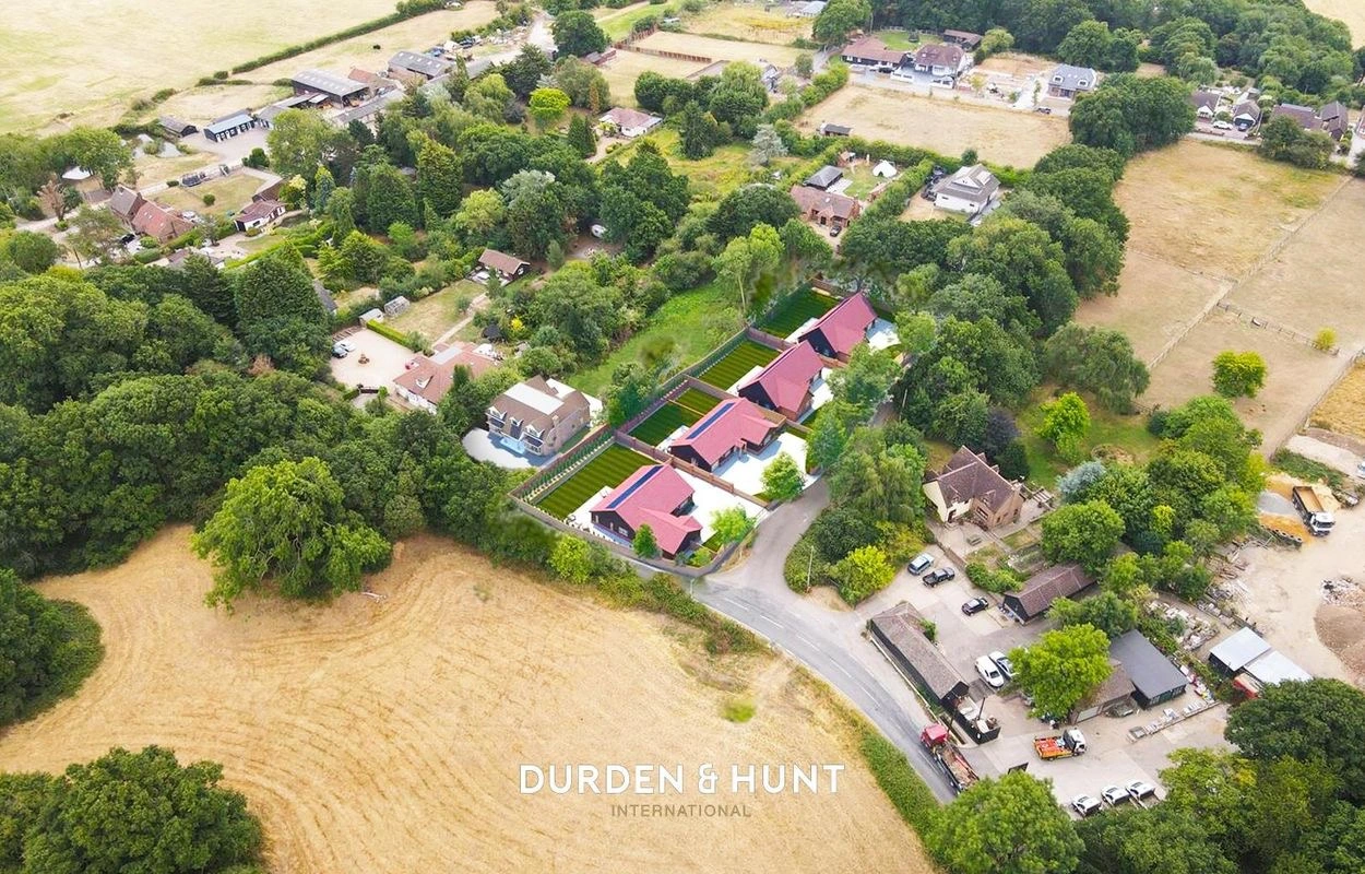 Aerial view of residential properties with red roofs surrounded by trees and fields, with Durden & Hunt International branding