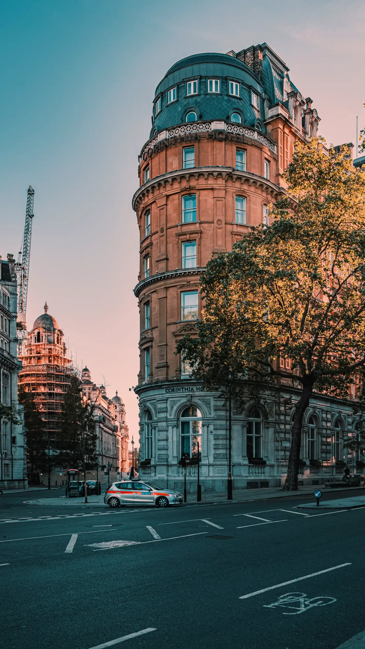 Victorian red brick tower building with turquoise cupola and ornamental ironwork, street-level view with surrounding period architecture