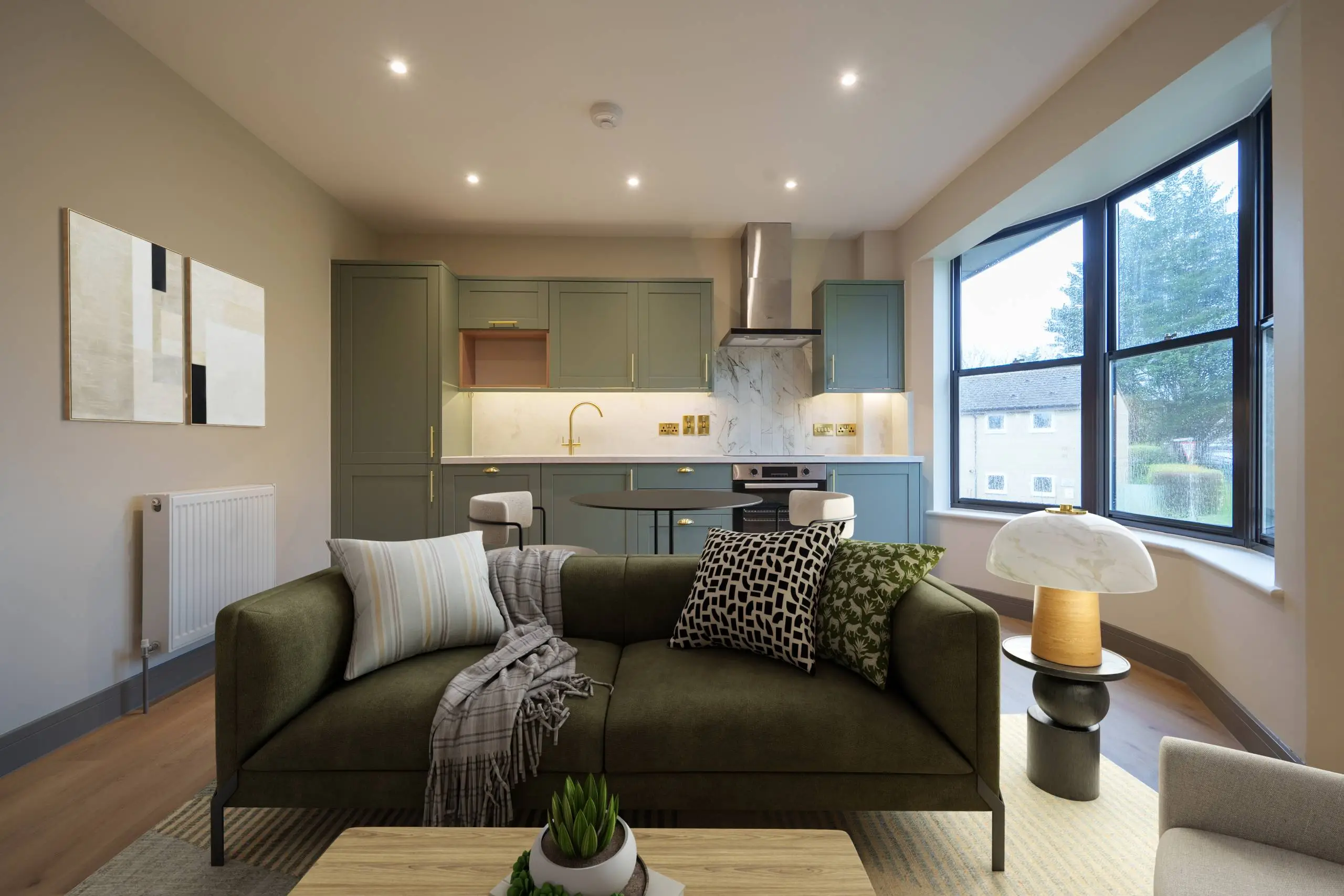 Open-plan living and kitchen area with olive green sofa, striped and patterned cushions, large windows overlooking trees, sage green cabinetry, marble splashback, and wooden flooring