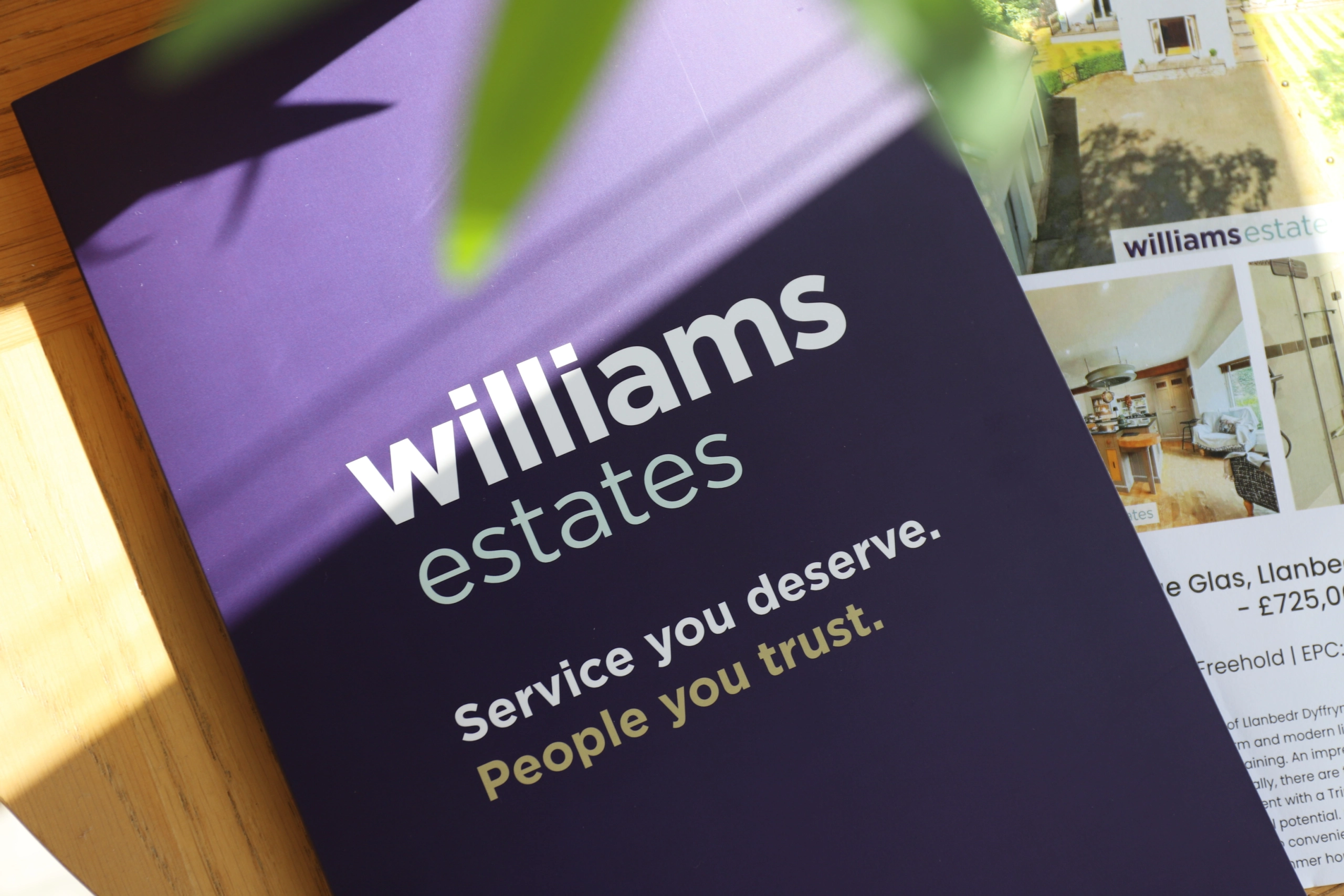Williams Estates brochure with tagline "Service you deserve. People you trust." on wooden surface