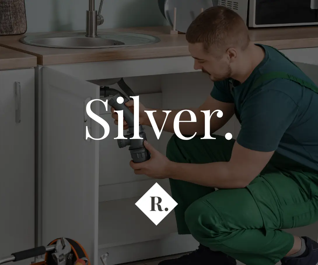 Person working under kitchen sink with plumbing tools and text overlay reading "Silver. R."