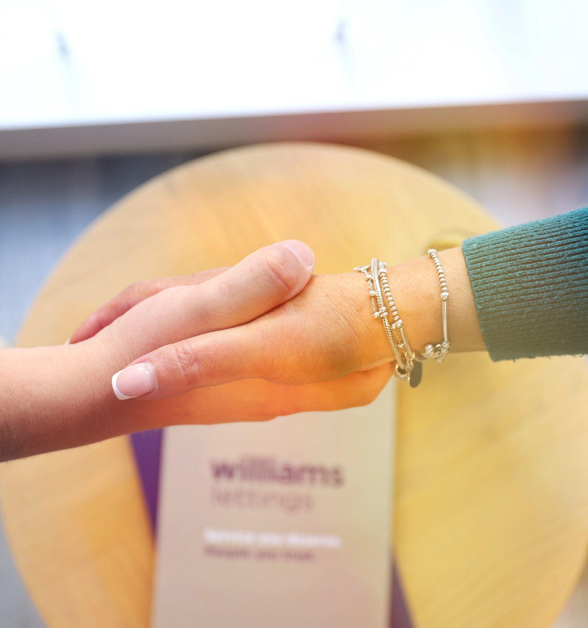 Hand with silver bracelets resting on yellow sphere, blurred building in background