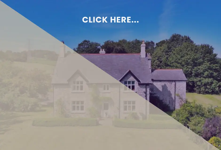Stone house with purple slate roof, chimneys and dormer windows, surrounded by trees and green grounds