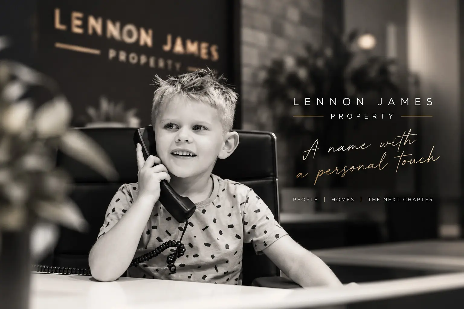 Young child holding a vintage telephone handset at a desk, black and white photograph with Lennon James Property branding and tagline "A name with a personal touch"