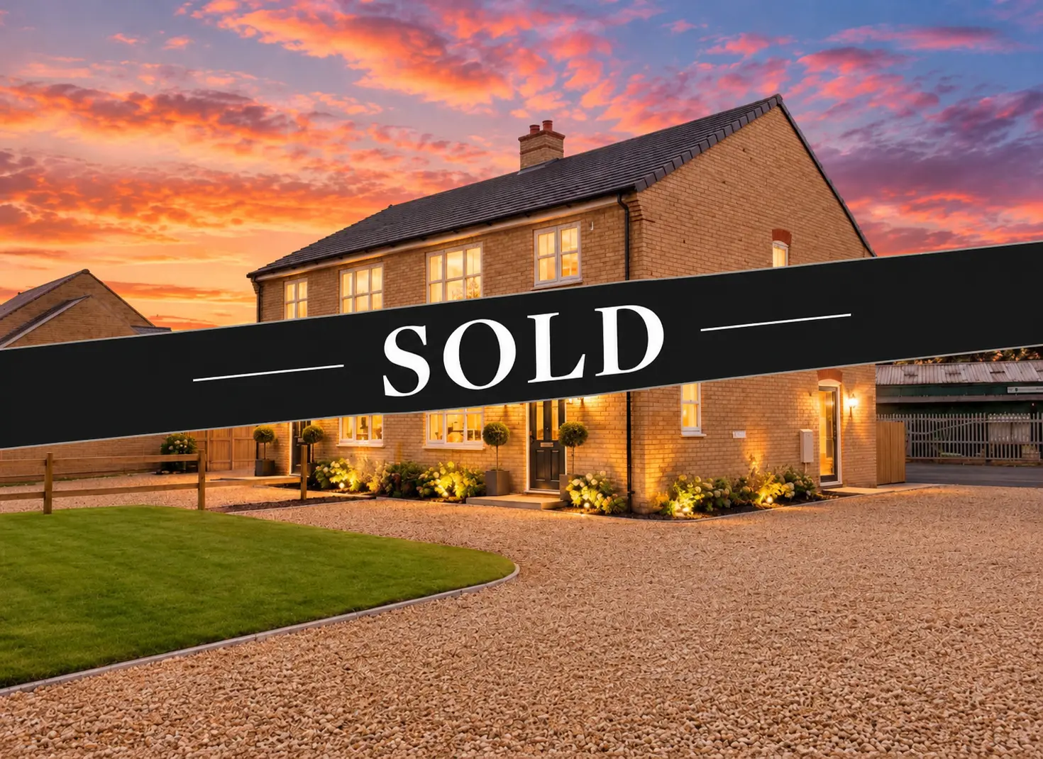 Brick house at dusk with illuminated windows and landscaping, overlaid with "SOLD" banner
