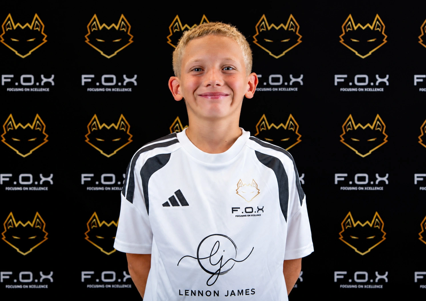 Young boy wearing white and black Adidas F.O.X sports shirt with signature and name