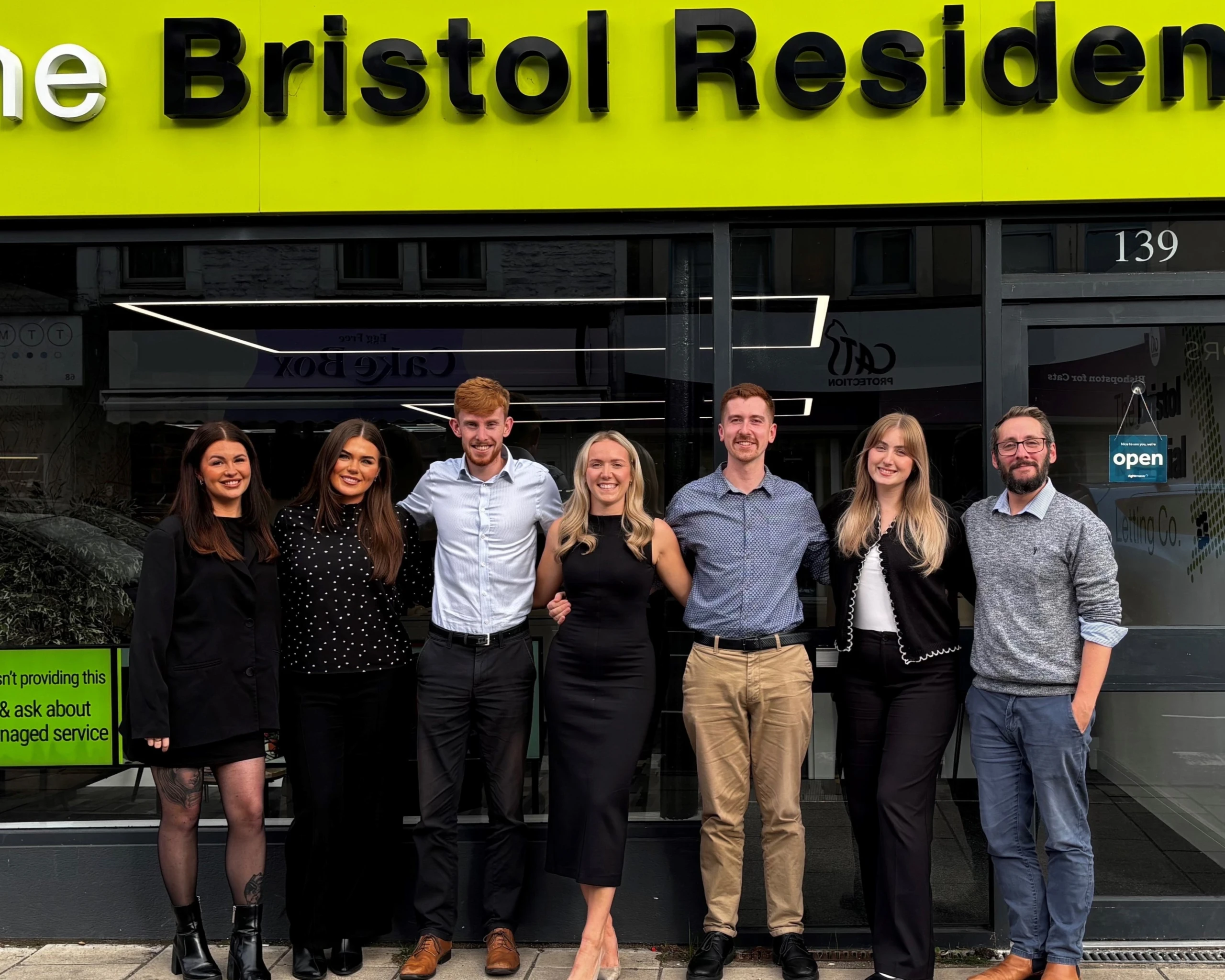 Seven people standing outside The Bristol Residential storefront at 139