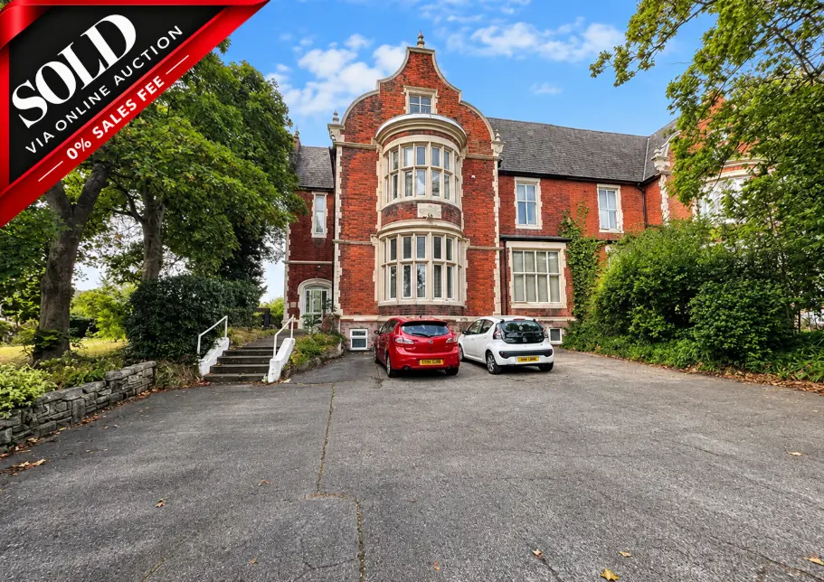 Red brick Victorian mansion with turret, surrounded by mature trees and ivy, two cars parked on driveway. Red banner reads 'SOLD VIA ONLINE AUCTION 0% SALES FEE'